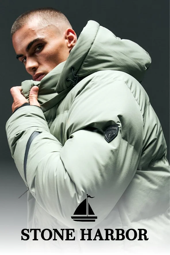 Ein Mann trägt eine beige Winterjacke mit Kapuze, Blick nach links, dunkler Hintergrund, darunter der Text "Stone Harbor" mit einem Segelschiff-Logo.