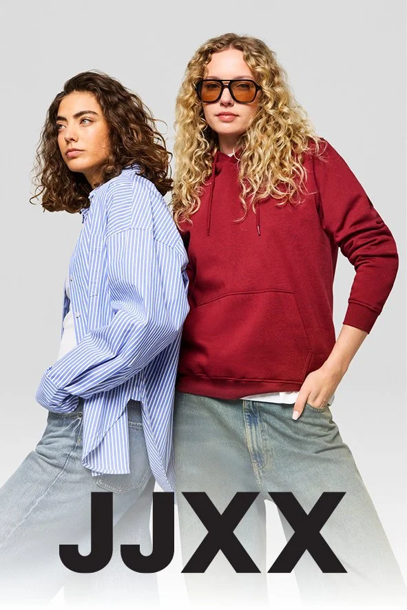 Zwei junge Frauen stehen nebeneinander, eine trägt eine blaugemusterte Bluse und die andere eine rote Kapuzenjacke mit Sonnenbrille.