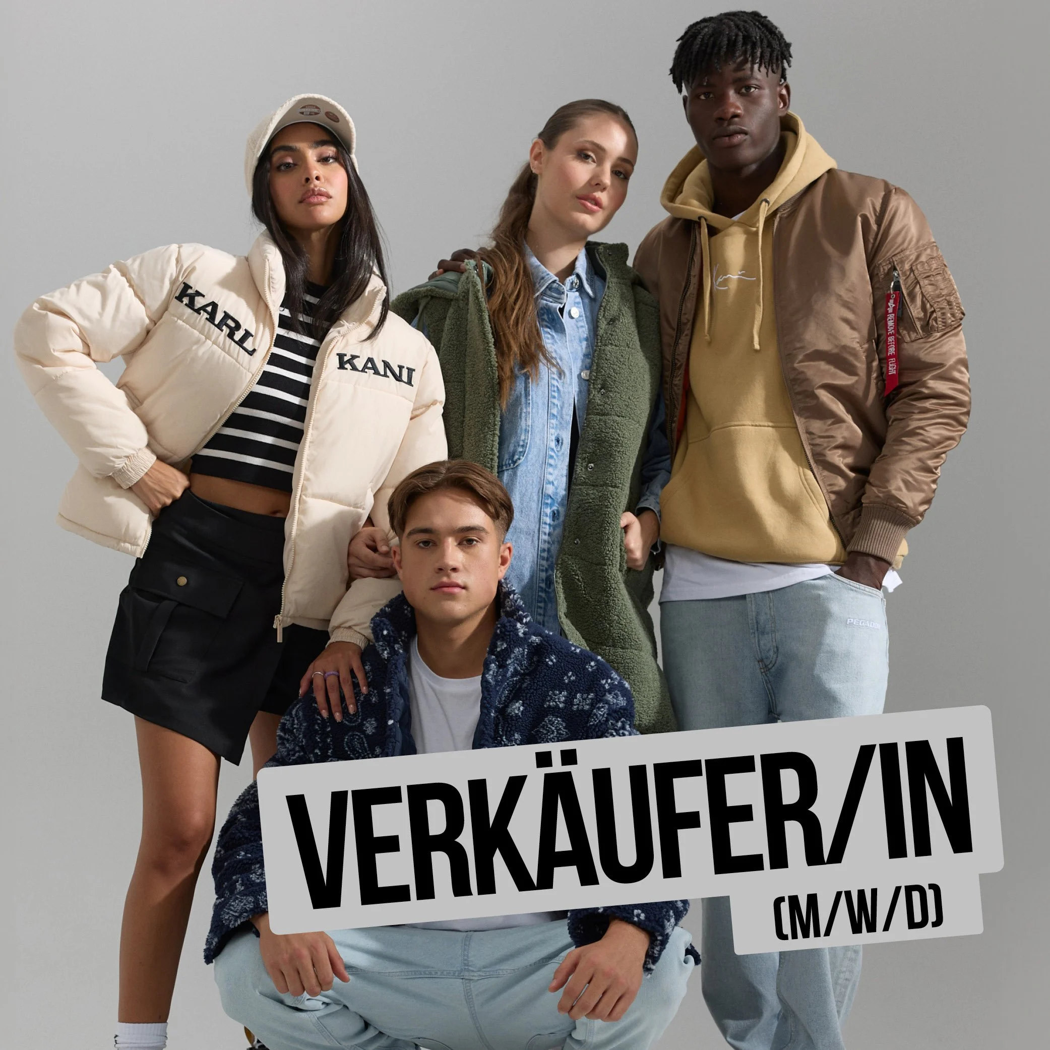Drei Menschen stehen vor einem grauen Hintergrund, einer hält ein Schild mit schwarzer Aufschrift: "VERKAUFT/IN".