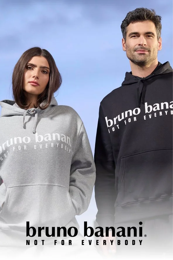 Ein Mann und eine Frau tragen graue bzw. schwarze Hoodies mit dem Logo "bruno banani" und dem Slogan "NOT FOR EVERYBODY" vor blauem Himmel.