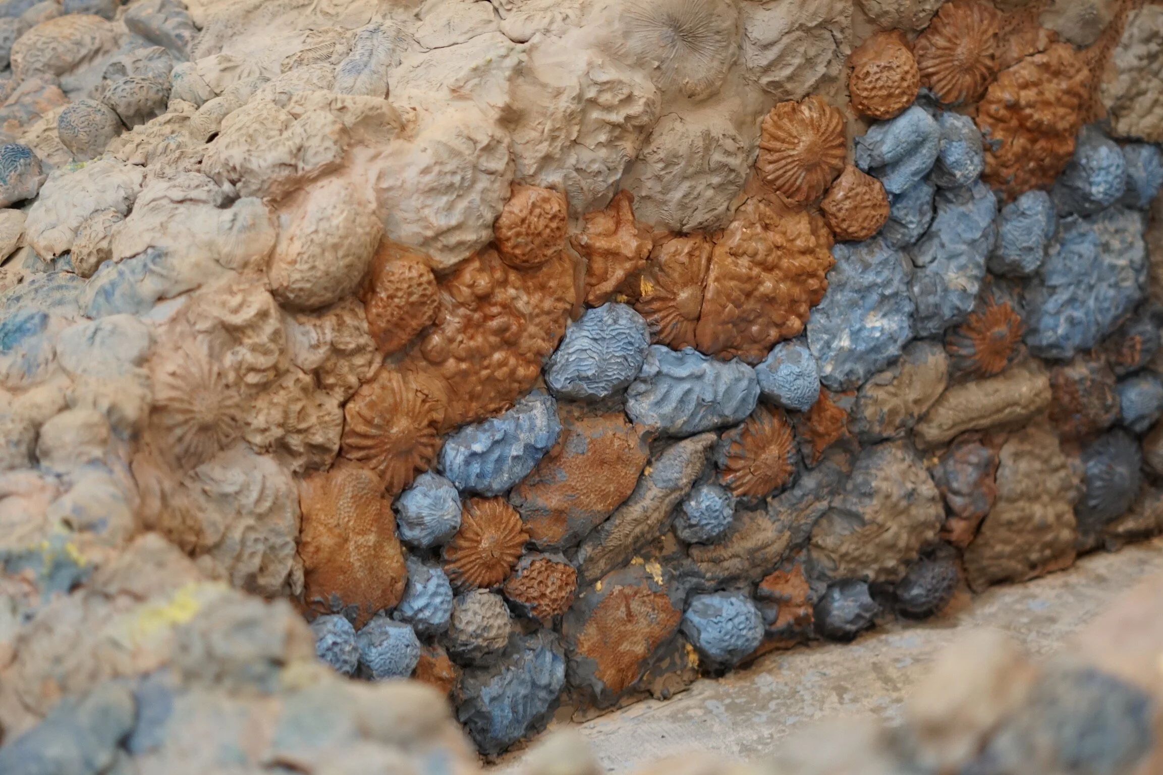 Close-up view of sculptural monumental sunken arches covered in clay forms like seashells and corals.