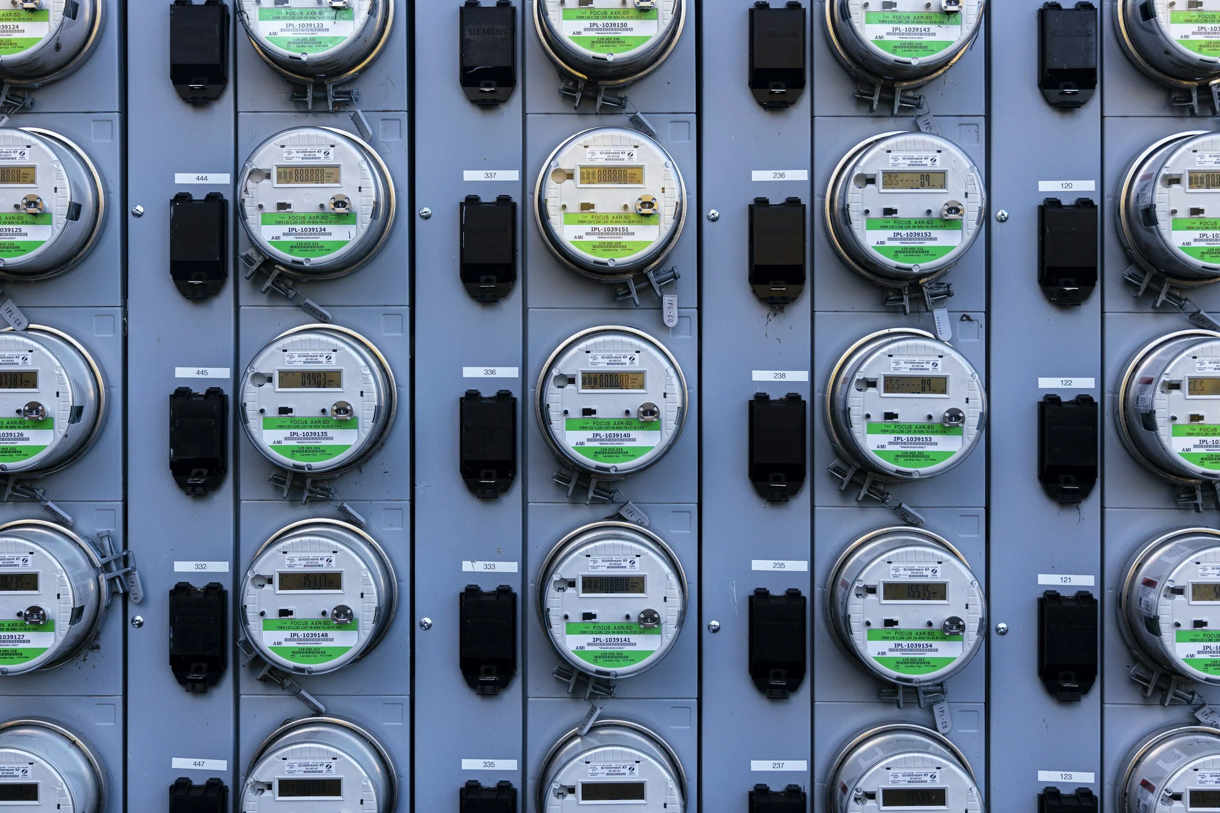 Rows of digital electricity meters mounted on a wall.