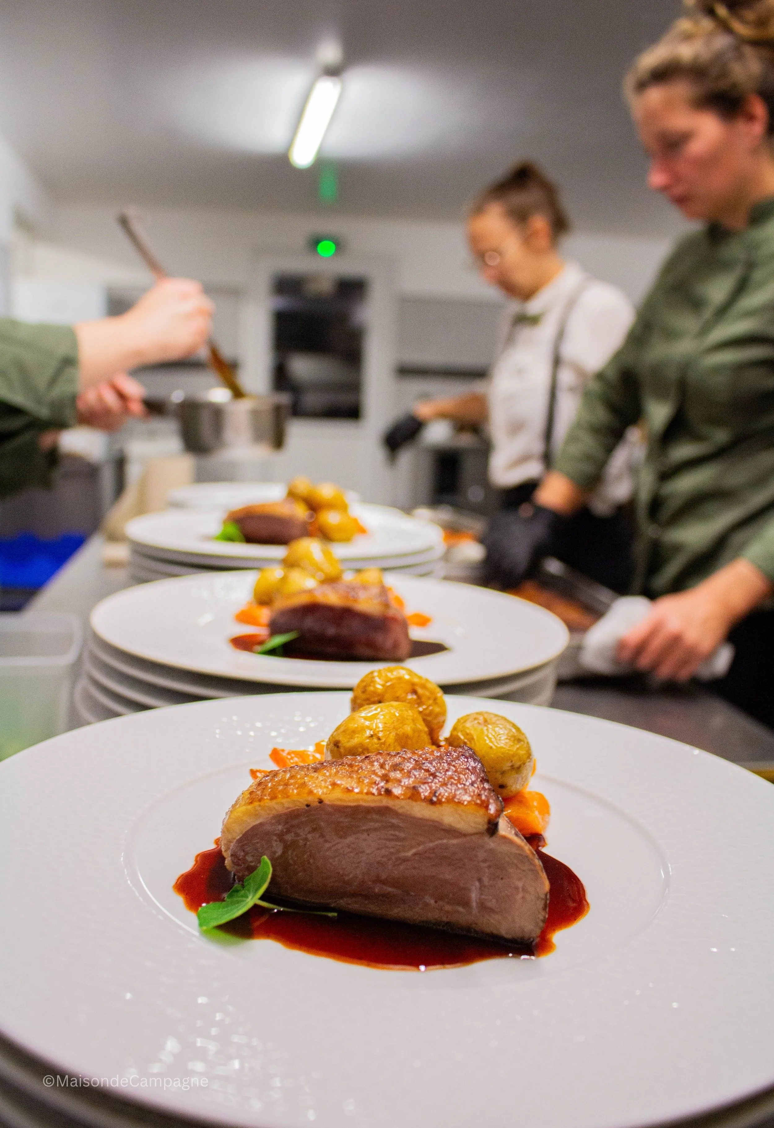 Cuisine haut de gamme pour événement. Assiette gastronomique avec viande, pommes de terre et sauce, en cours de préparation par des chefs en cuisine.