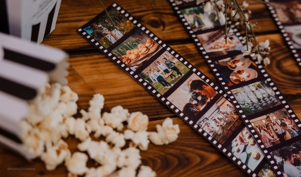 Une bande de films photographiques avec des images de mariage et une boîte à pop-corn sur une table en bois.