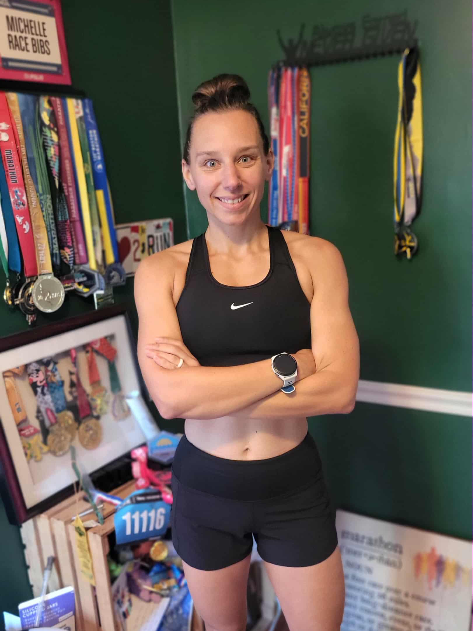Michelle Carr smiling in front of her display of race medals