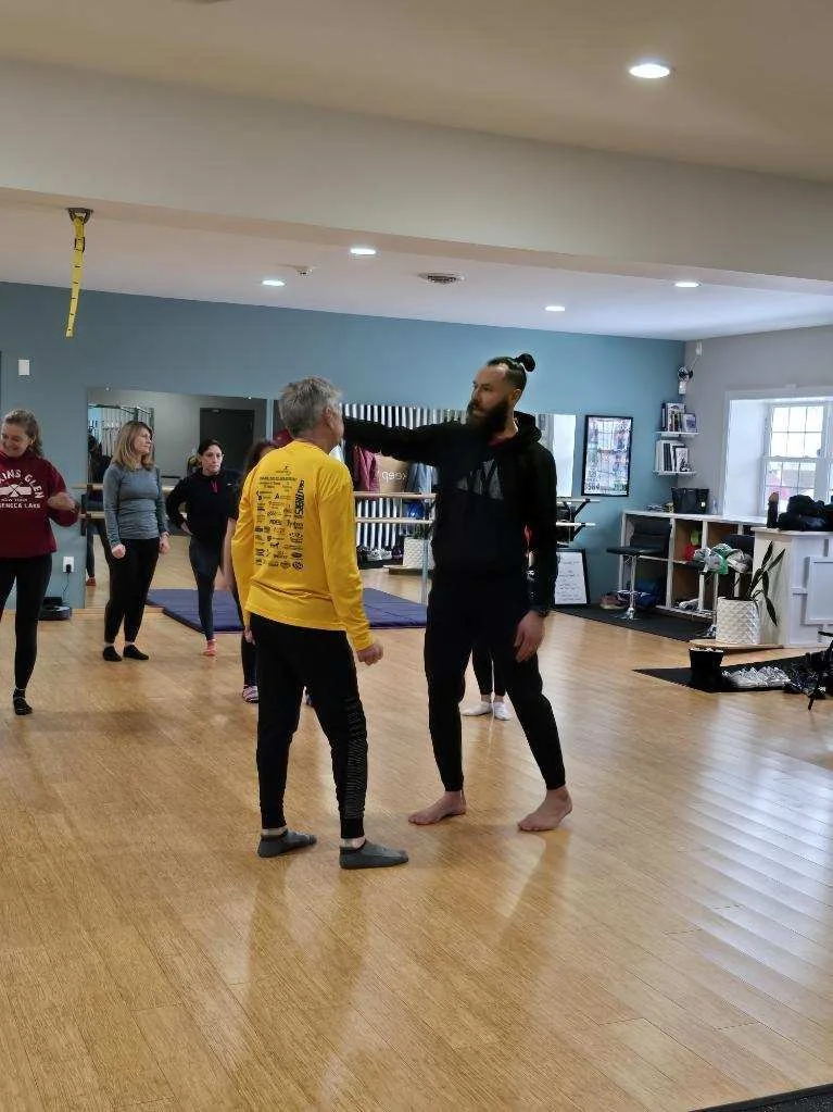 A group of people at Keep Fit in Guilderland, with Master Kyle Phillips of Nisky Martial Arts demonstrating a move by placing his hand on a man's head.