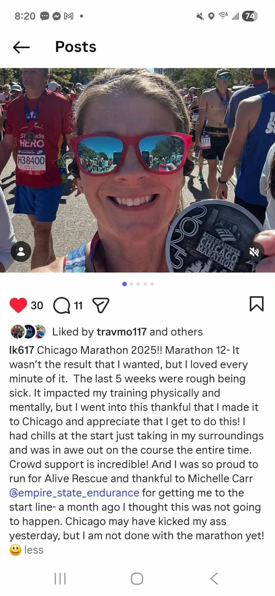 Woman smiling with sunglasses holding a Chicago Marathon medal, surrounded by runners at the race event.