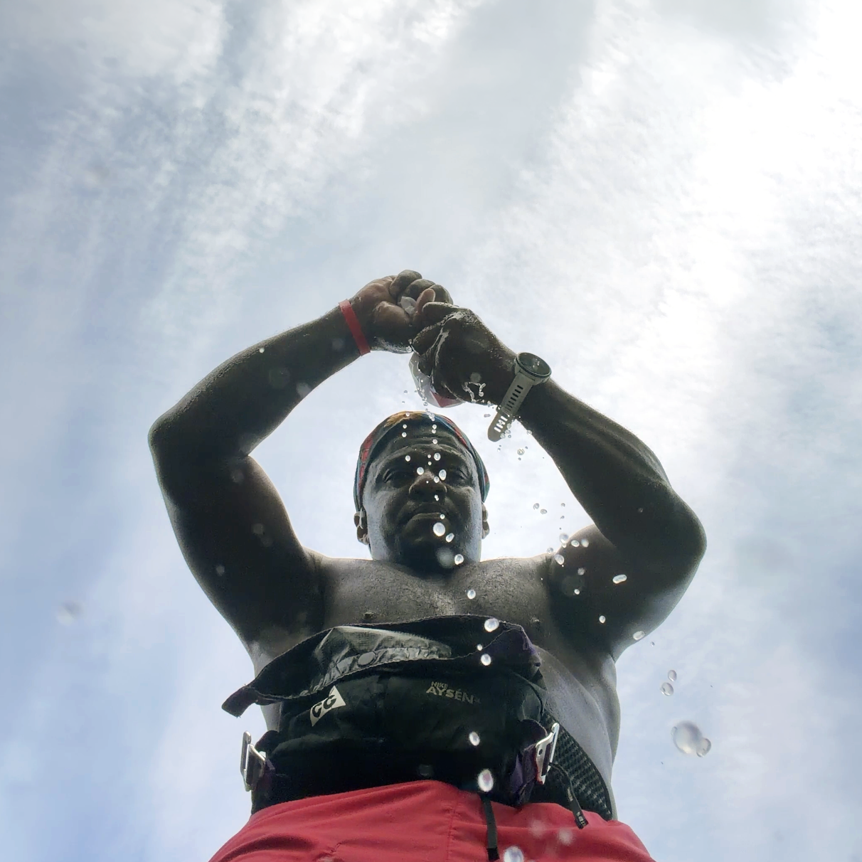 Runner wringing sweat out of a shirt after a hot summer run, demonstrating the importance of hydration and electrolyte replacement during endurance training.