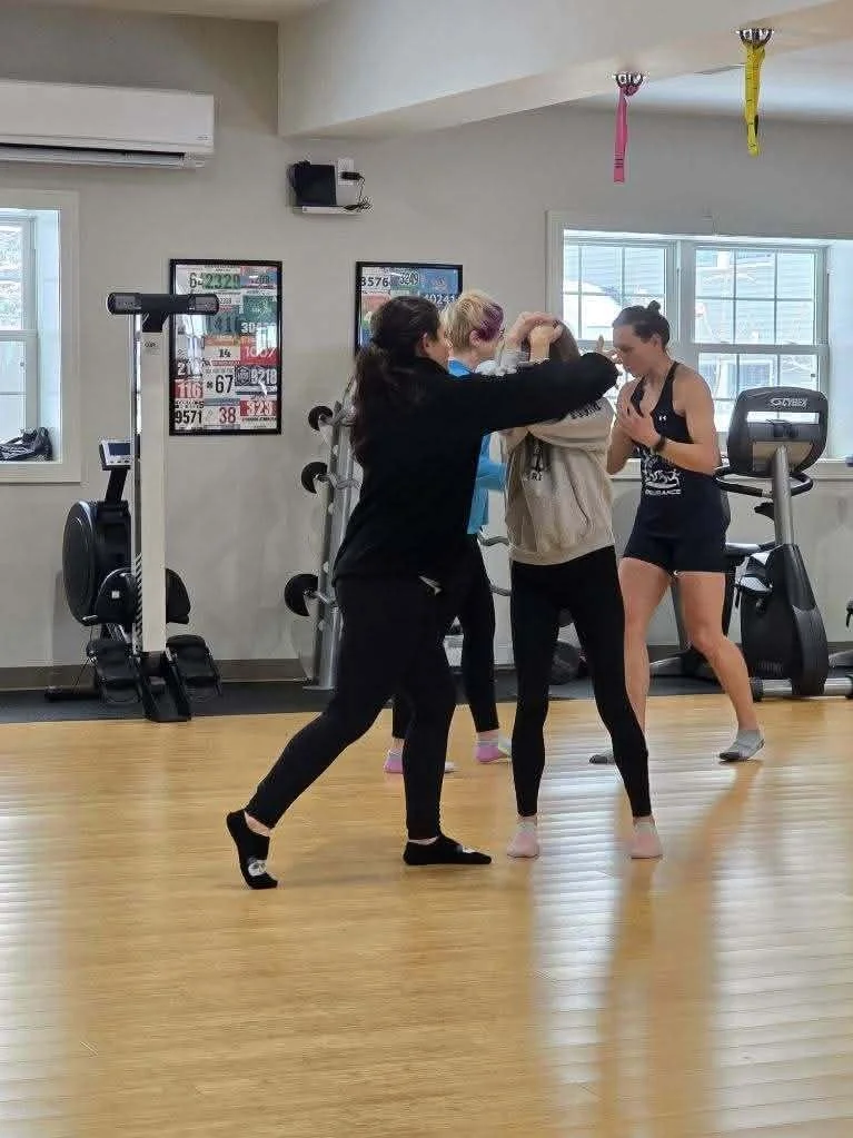 Two women practicing self-defense or martial arts. Master Kyle Phillips demonstrating martial arts techniques to a group of women and children at Keep Fit in Guilderland, NY.