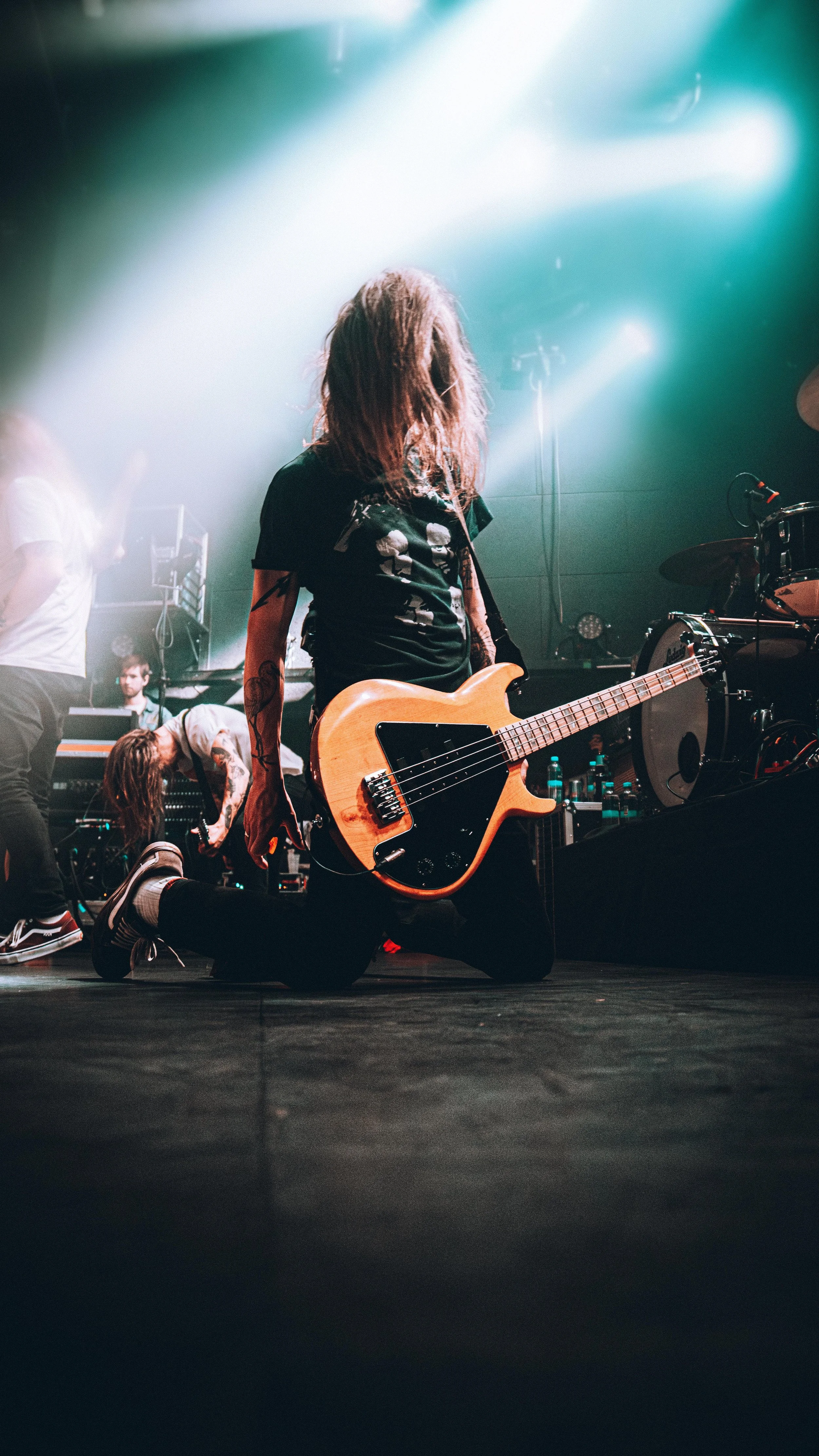A musician kneeling on stage with a guitar during a live concert.