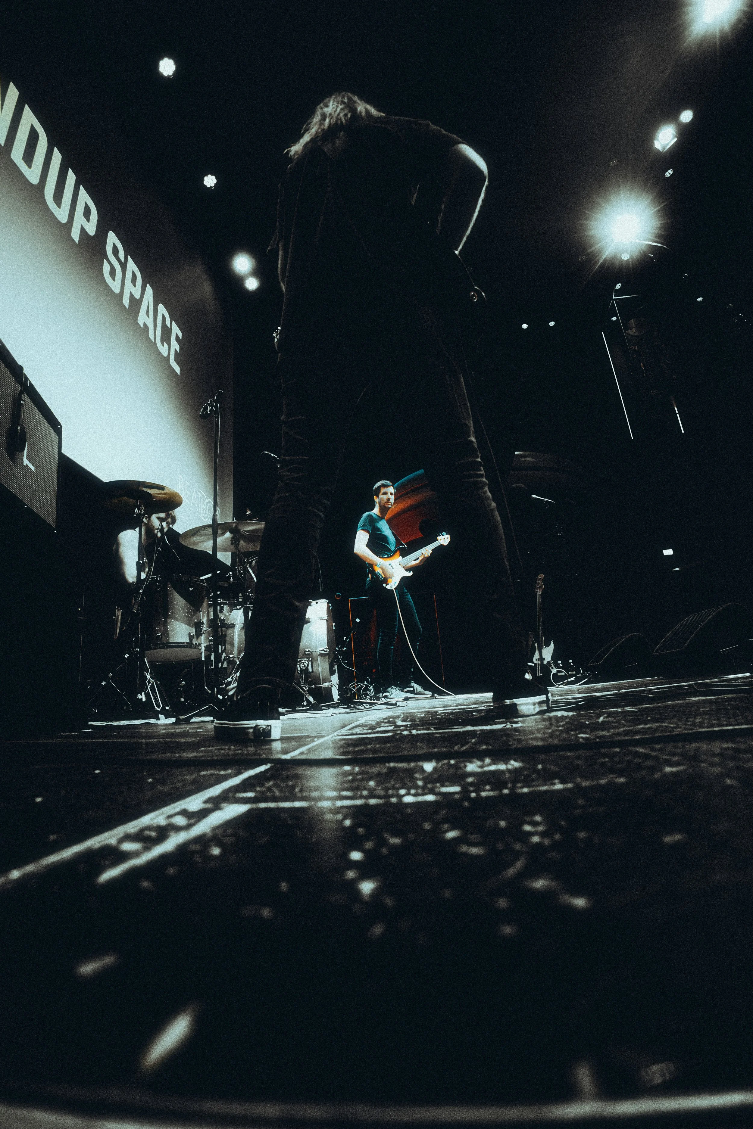 A band performing on stage with a large screen displaying 