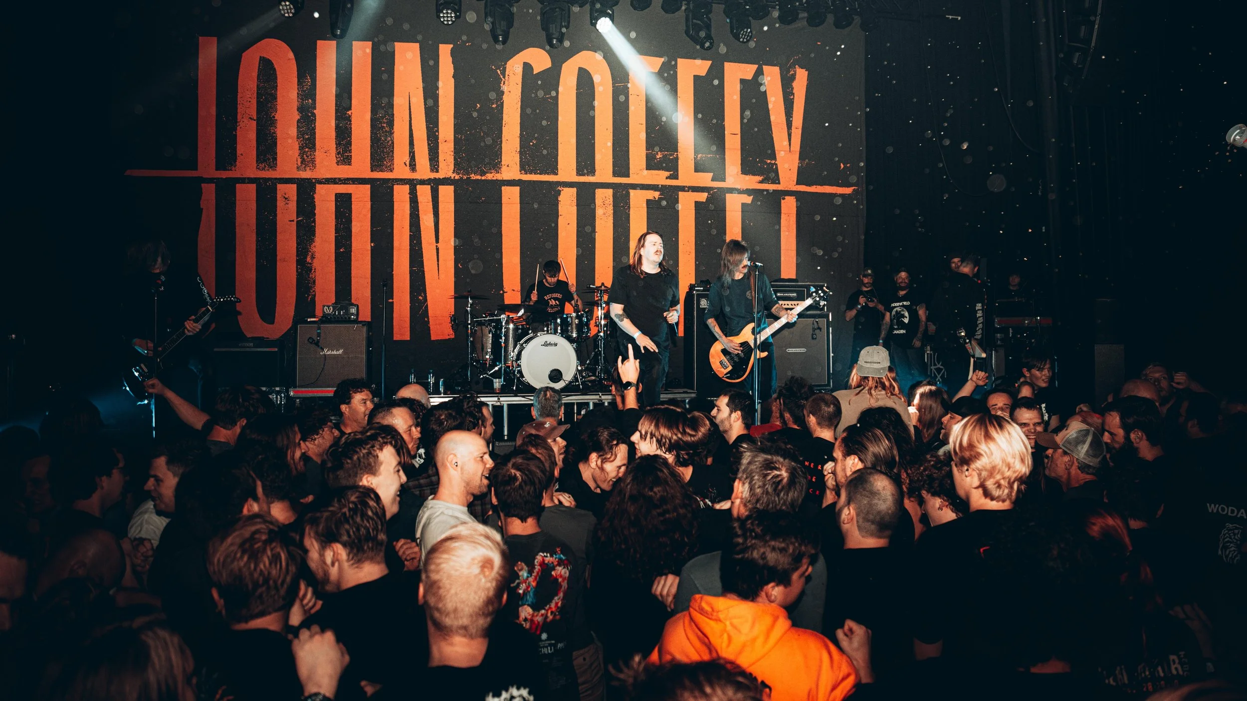 A live concert with a band performing on stage and a crowd of people watching.