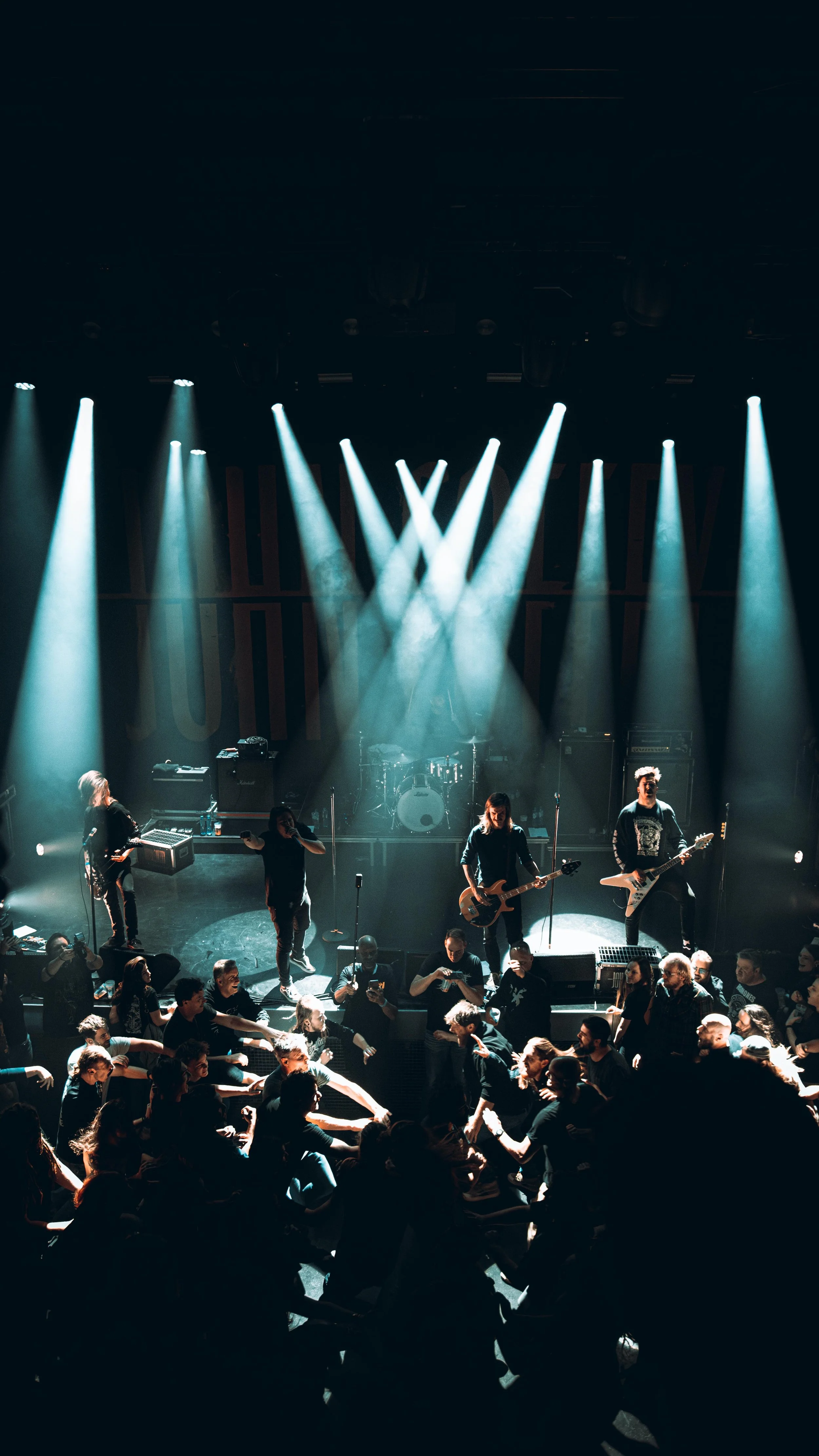 Live music concert with a band on stage and dancing crowd in front.
