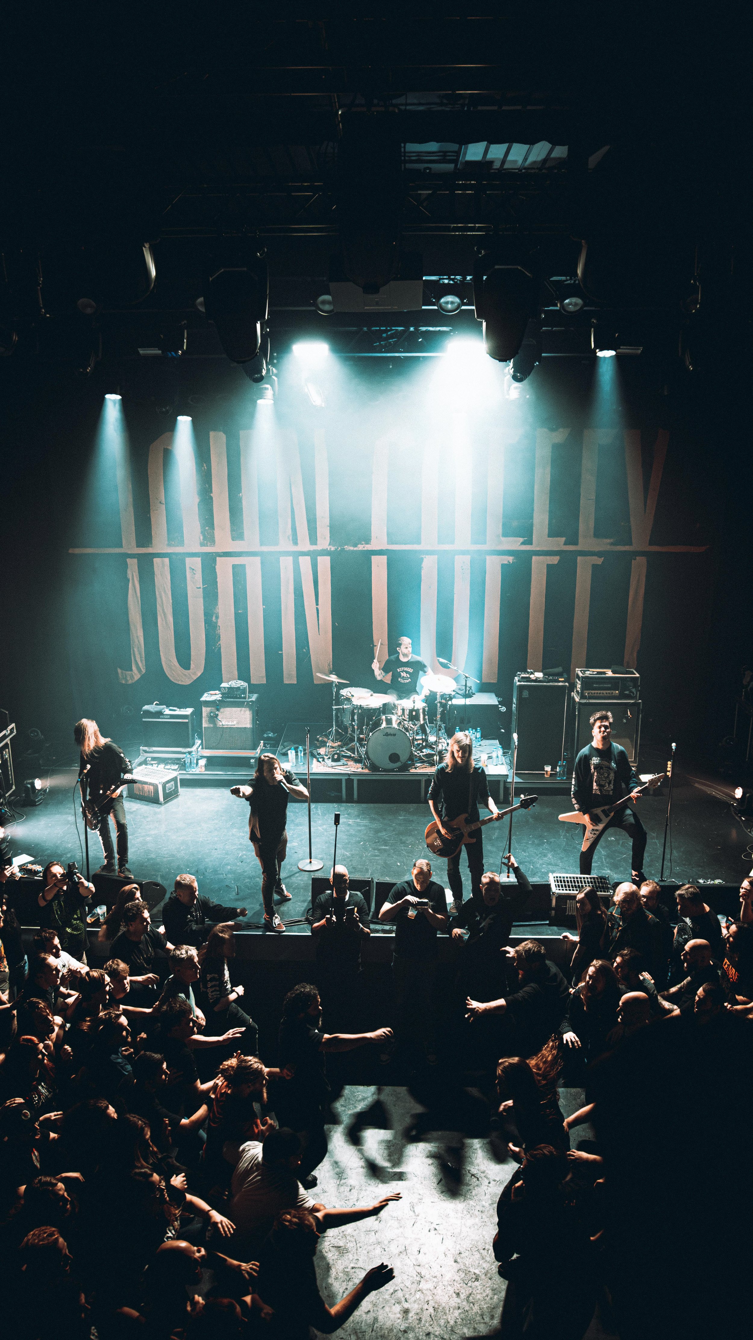 A band performs on stage at a concert venue with an audience dancing and enjoying the music.