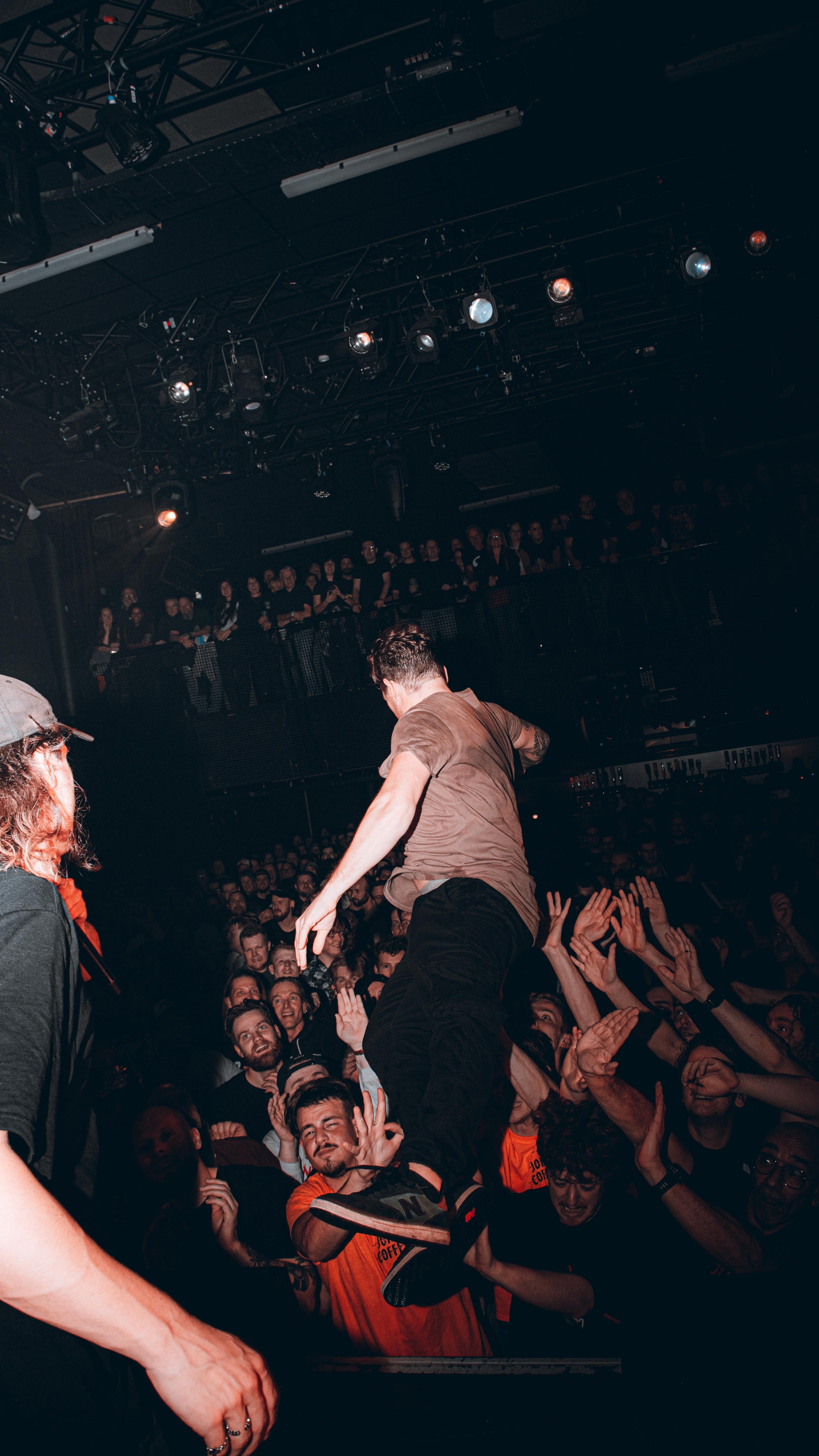 A musician performing on stage at a concert with an enthusiastic crowd reaching out and cheering.