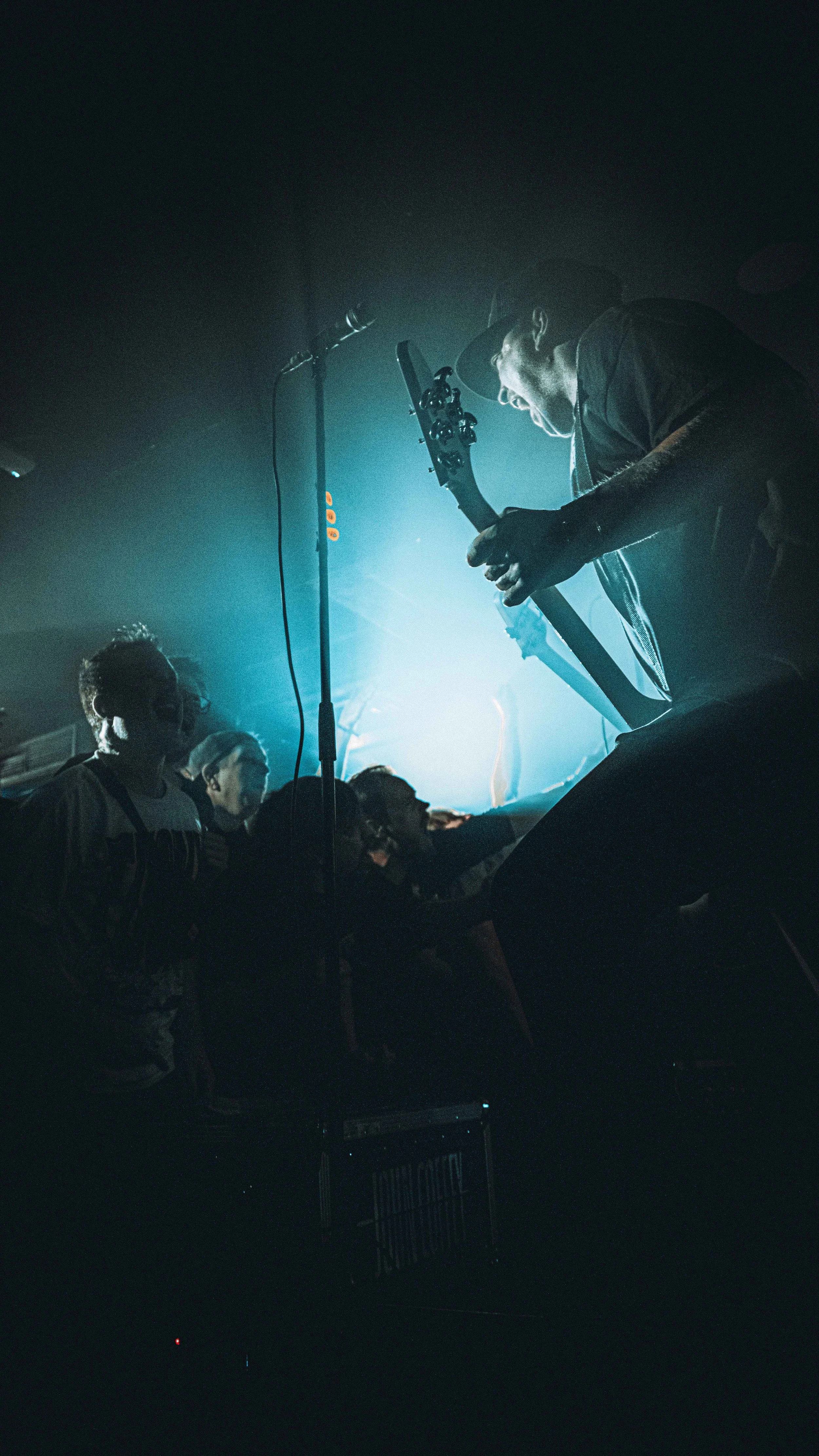 Musicians playing guitars on stage in a dark, vibrant concert setting