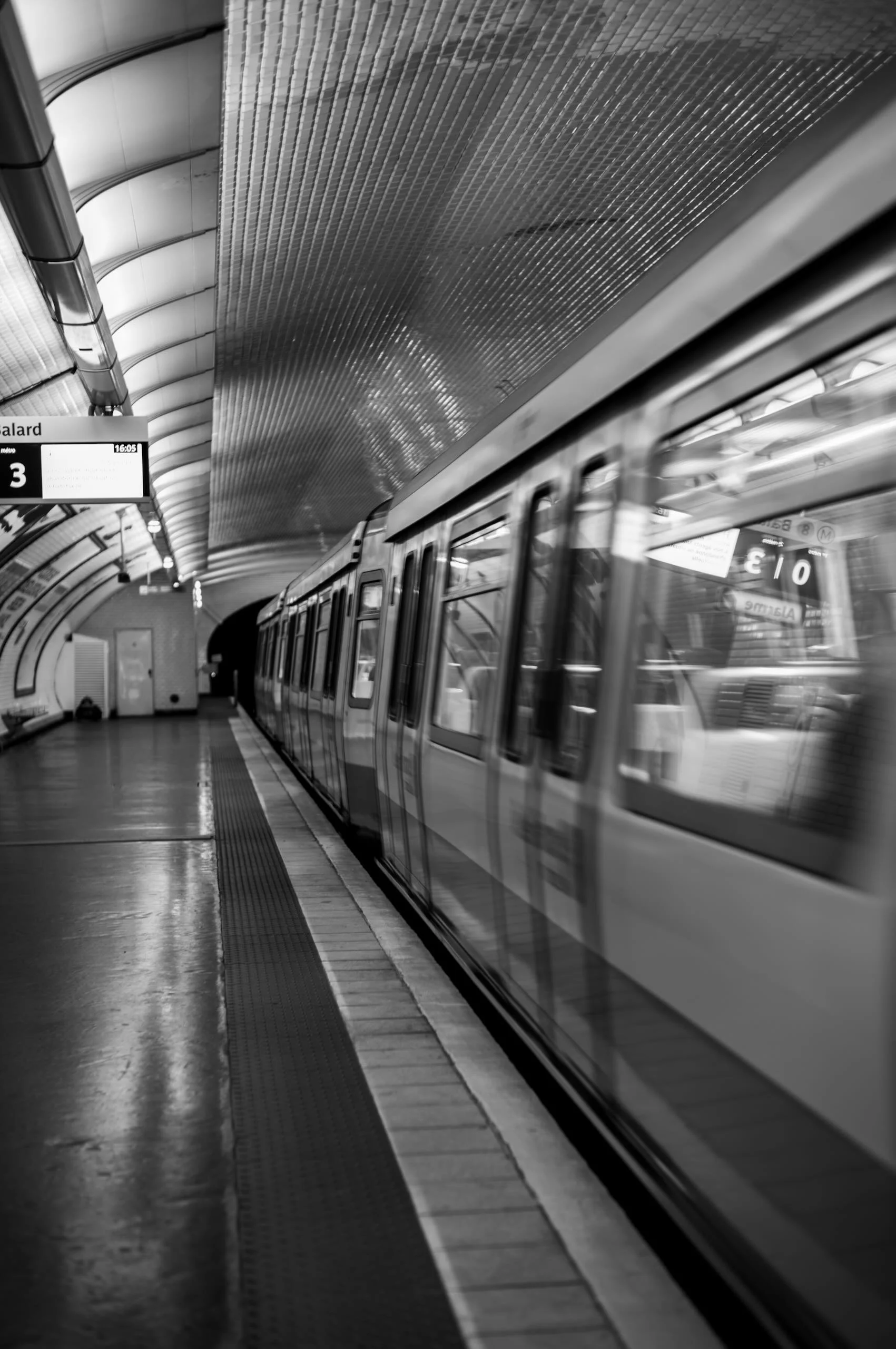 Un métro dans une station souterraine en noir et blanc.