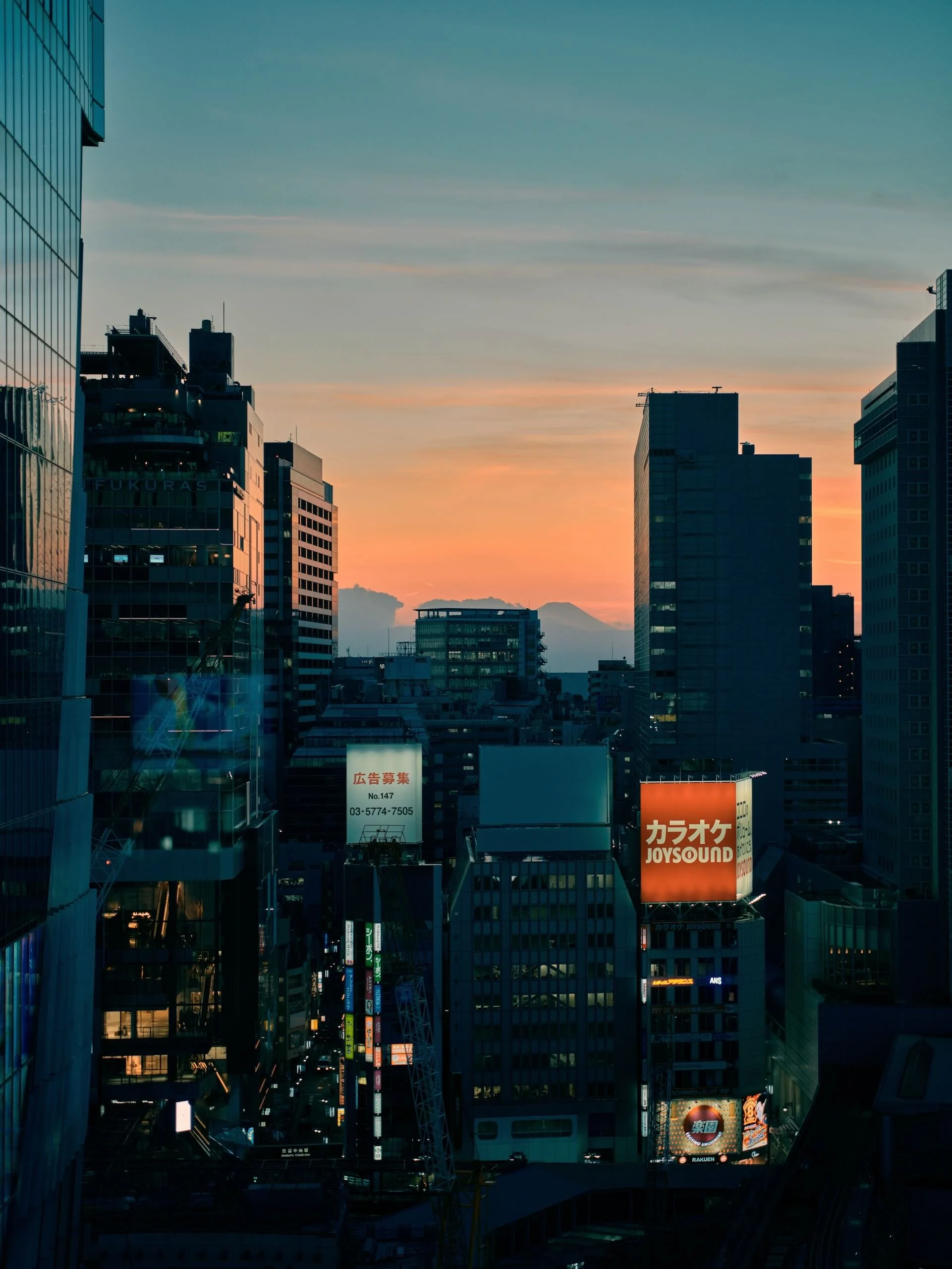 Vue urbaine de gratte-ciel avec un coucher de soleil dans une grande ville japonaise, montrant des enseignes lumineuses en japonais