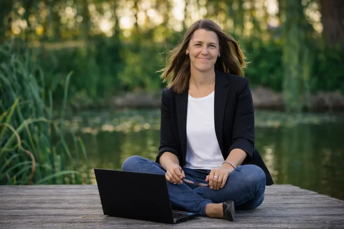 Jeannine Reimer arbeitet mit Laptop am See in der Natur