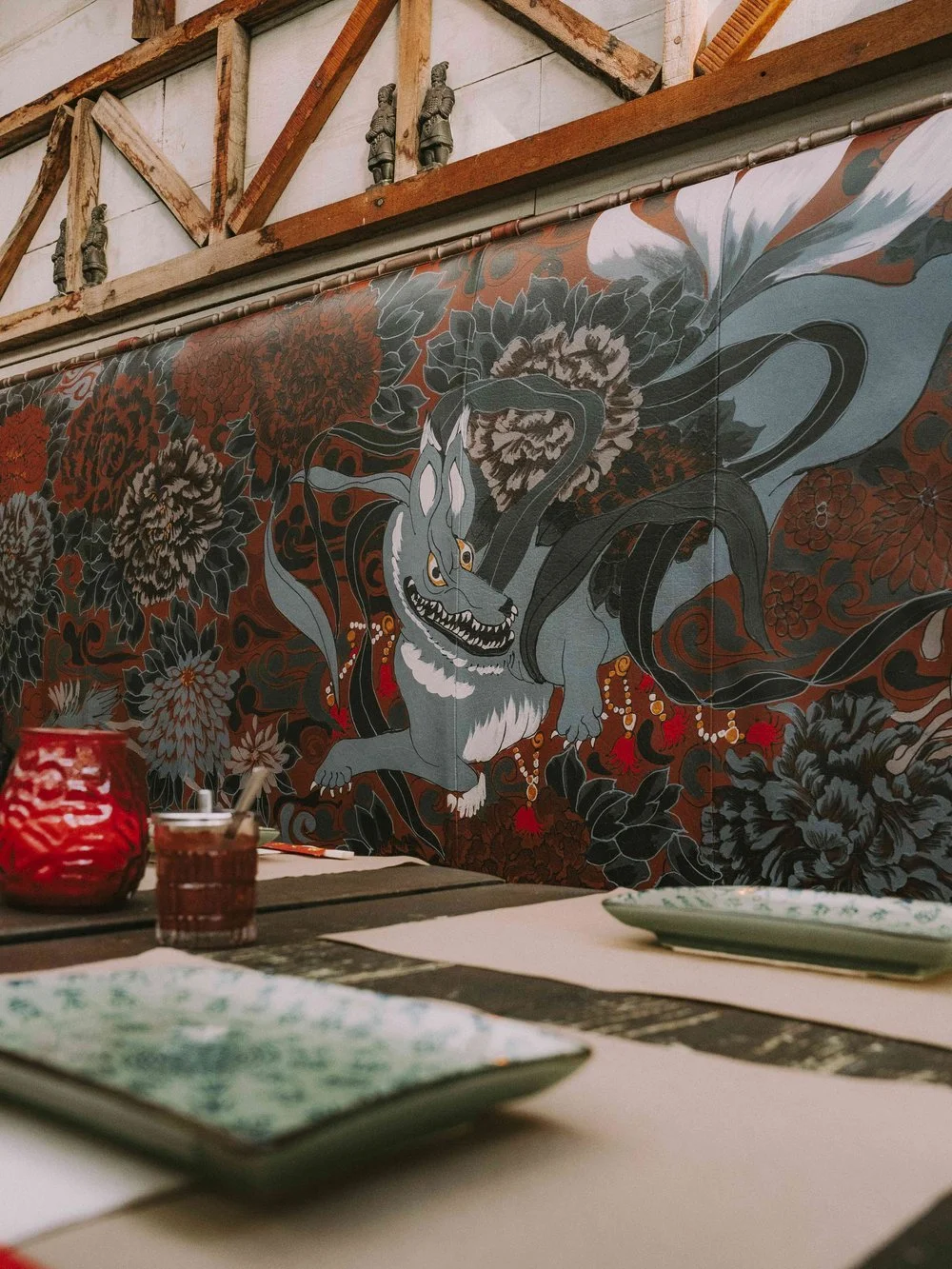 Decorative mural featuring a stylized dragon surrounded by flowers, with traditional Asian motifs in a restaurant or cafe setting.
