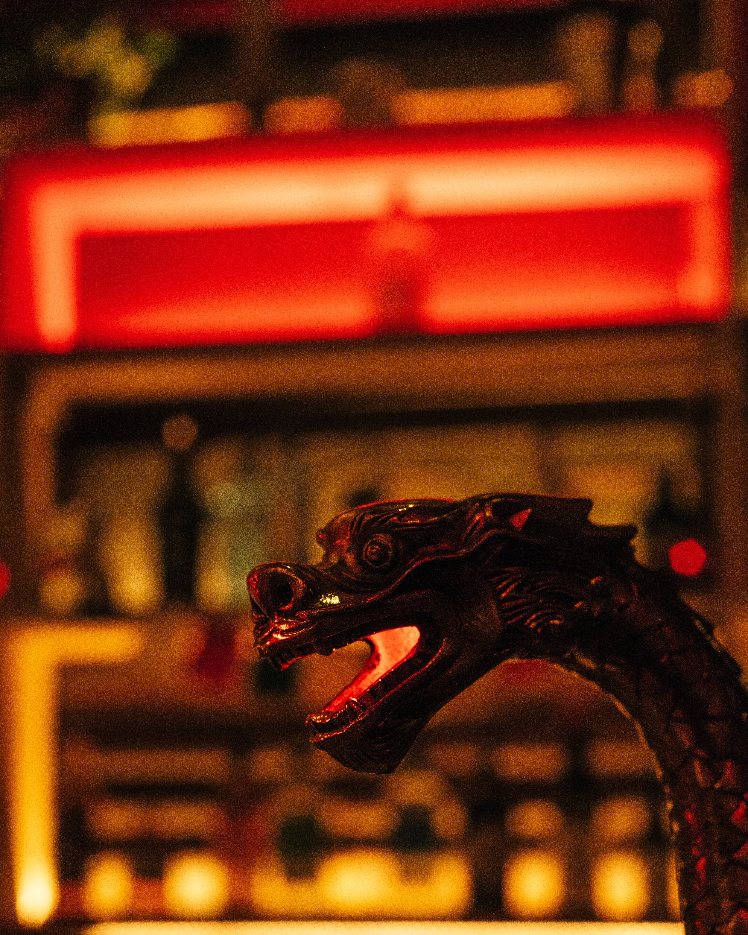 Close-up of a black dragon sculpture with red lighting in the background.