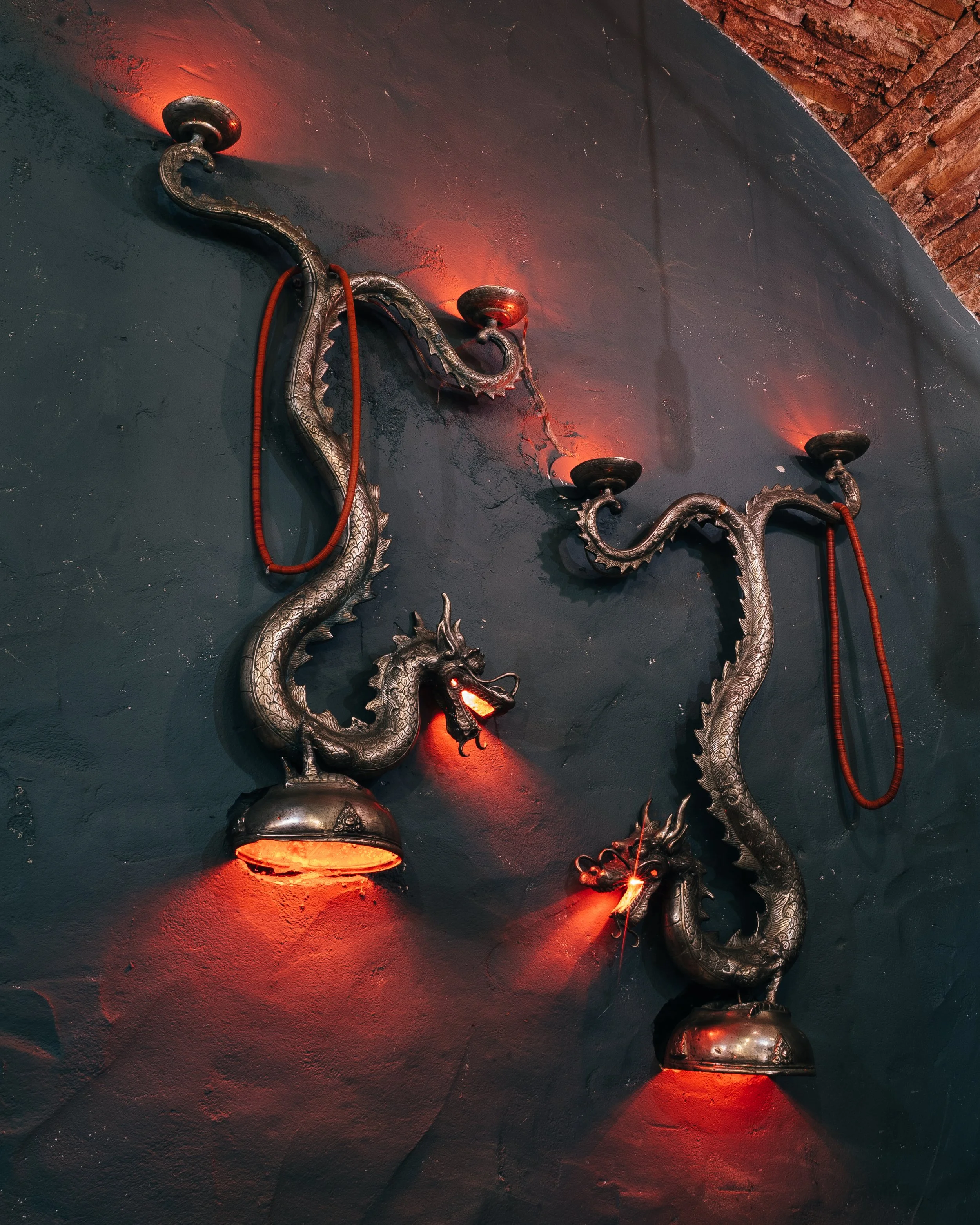 Decorative dragon-shaped wall sconces with red lighting on dark wall