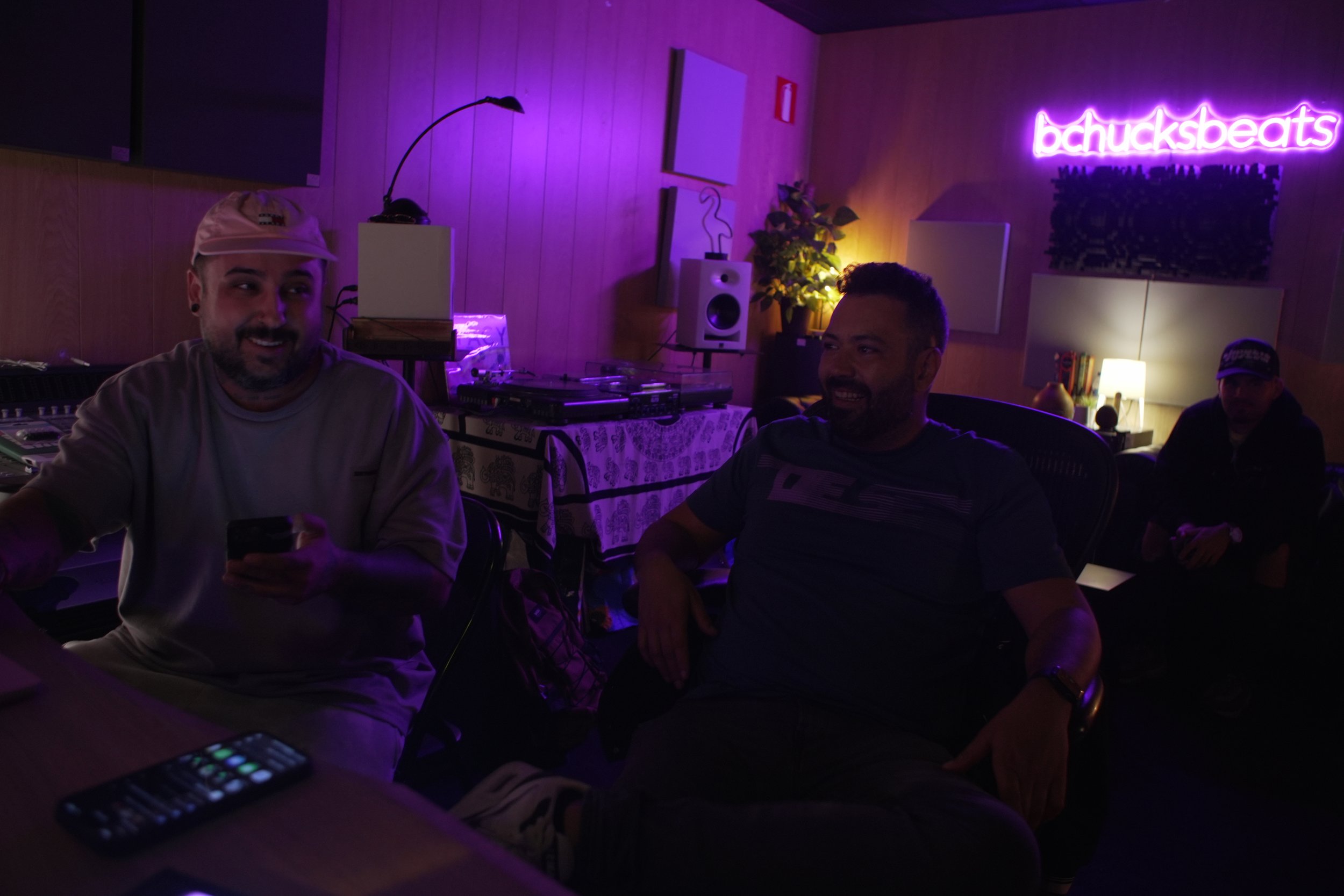 Grupo de personas en una sala con iluminación morada y un cartel de neón que dice 'bchucksbeats'.