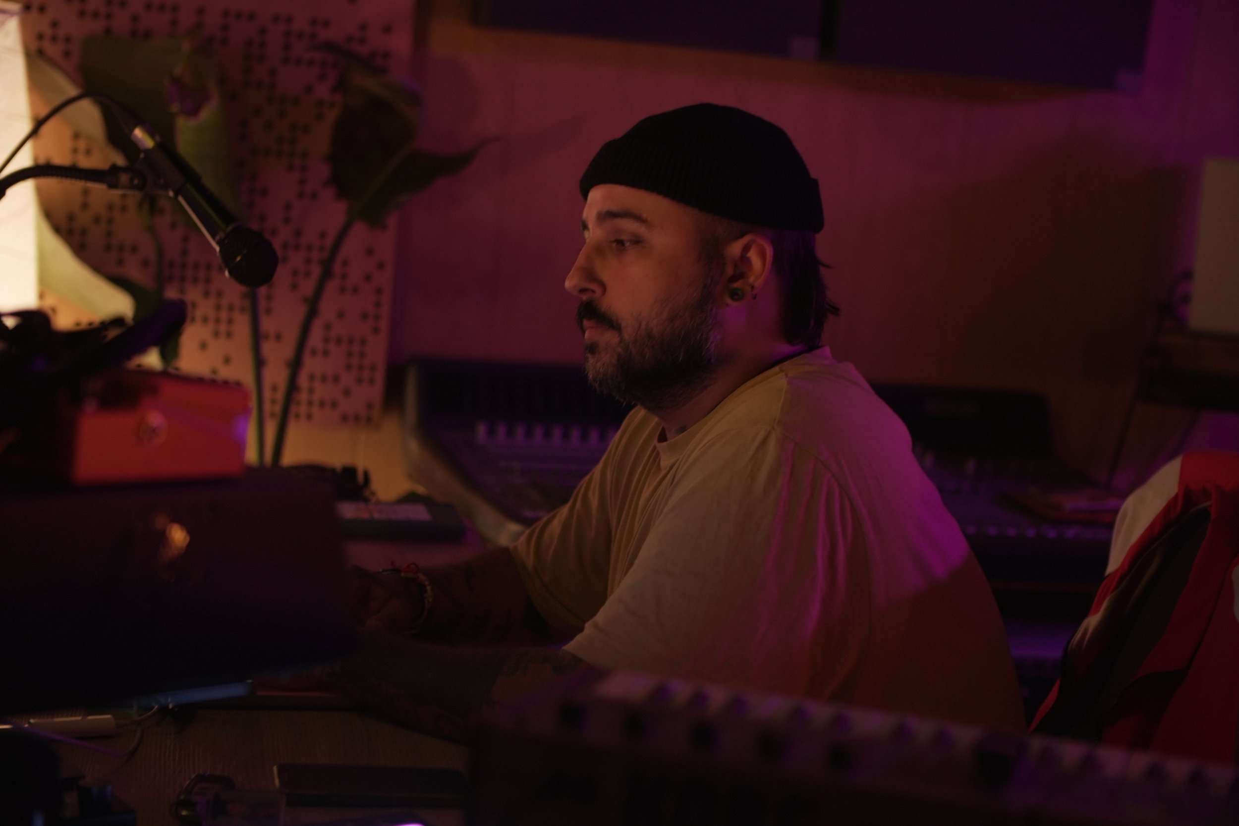 Persona tocando piano en un estudio musical con iluminación tenue y ambiente íntimo.