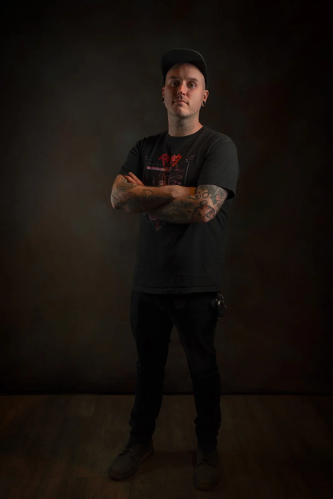 Andrew stands with arms crossed on a black background.