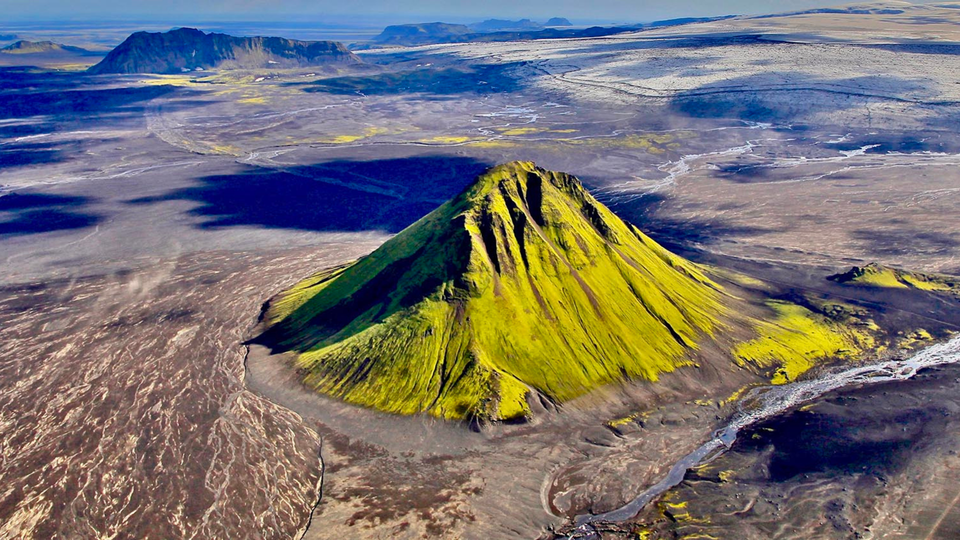 Green Mælifell mountain rising from black volcanic sands