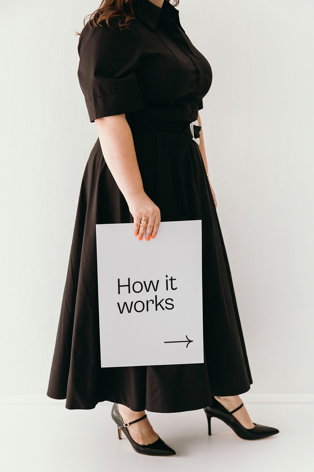 A woman holding a sign that says how it works pointing to the details on the right