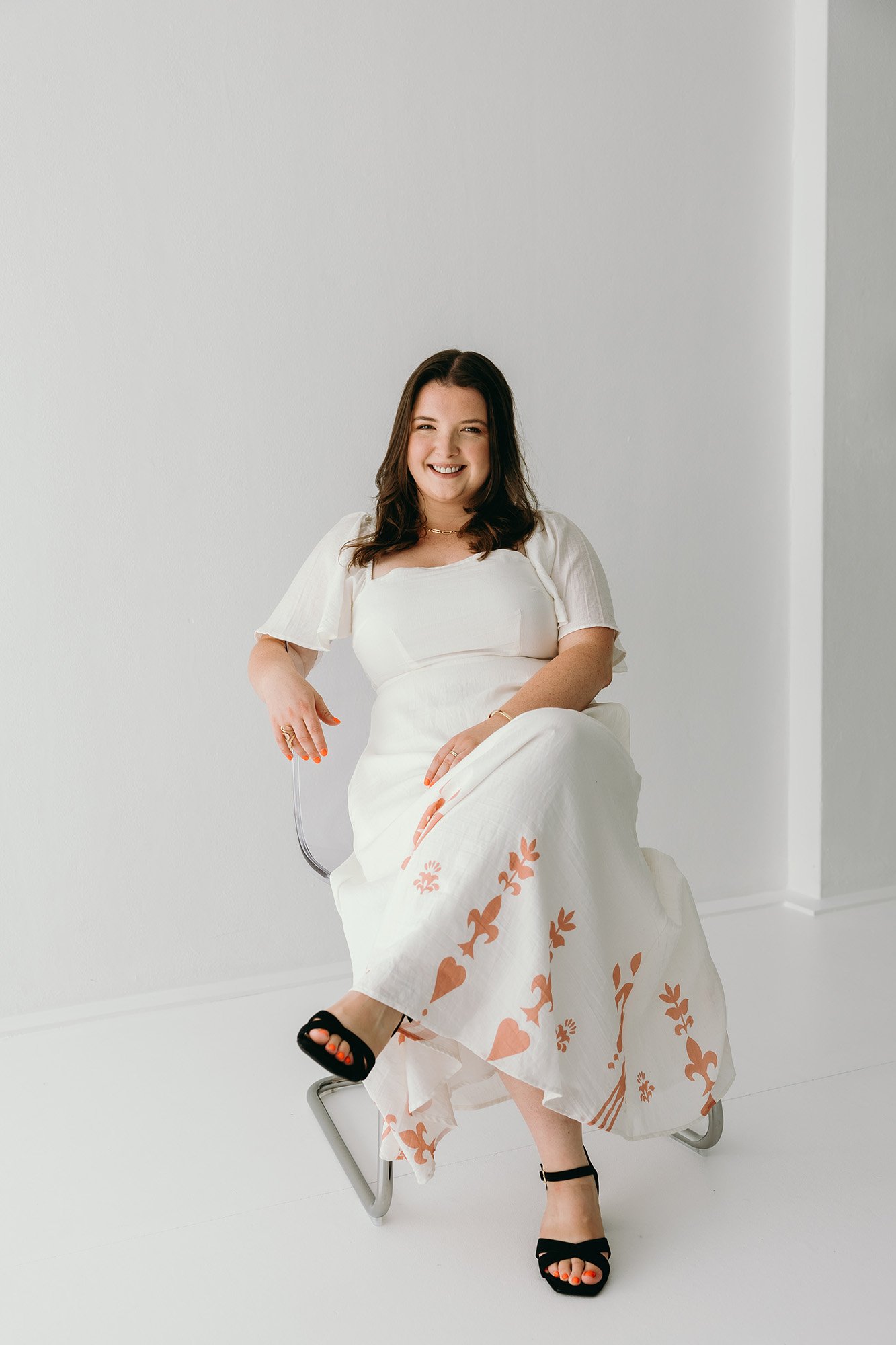 Lauren from Unravel smiling warmly in a white dress with orange florals representing a friendly and trustworthy partnership