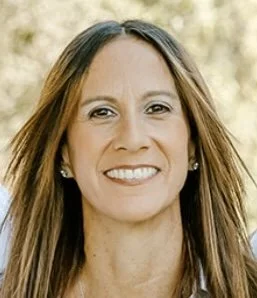 Close-up of a smiling woman with long brown hair outdoors