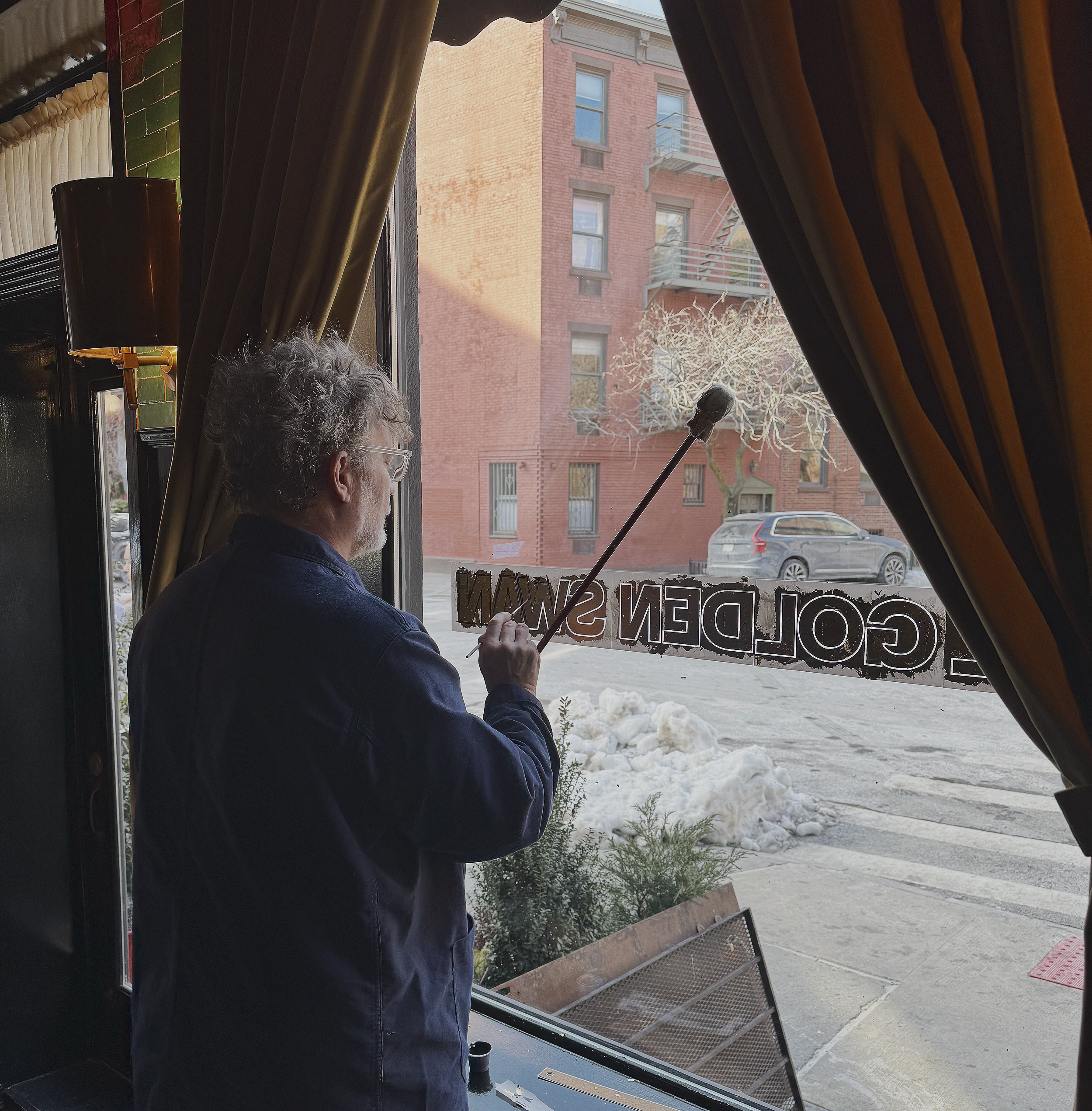 Gold leaf window signage being applied by hand at The Golden Swan restaurant in the West Village.