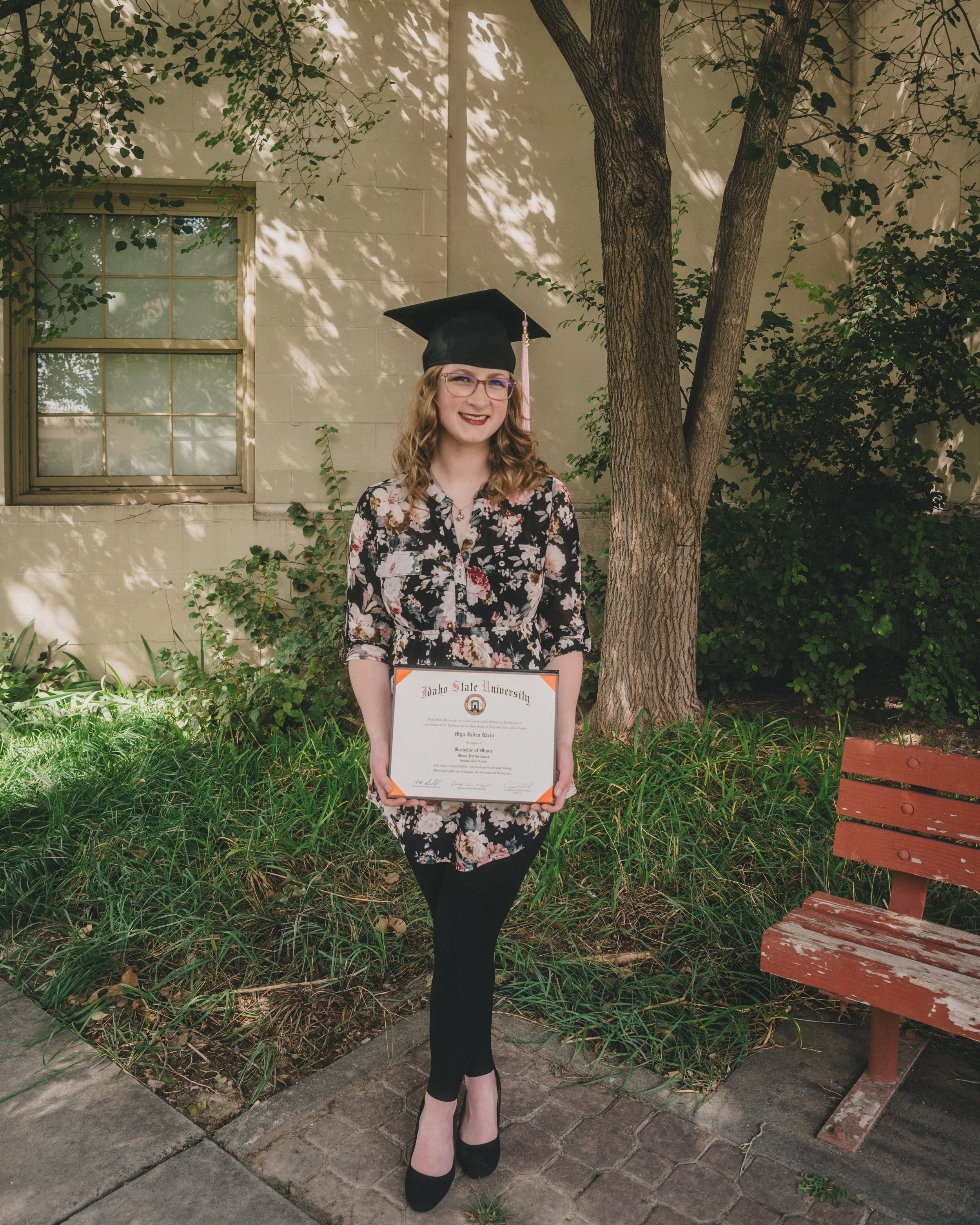 women at idaho state university standing with her diploma during a graduation shoot on campus