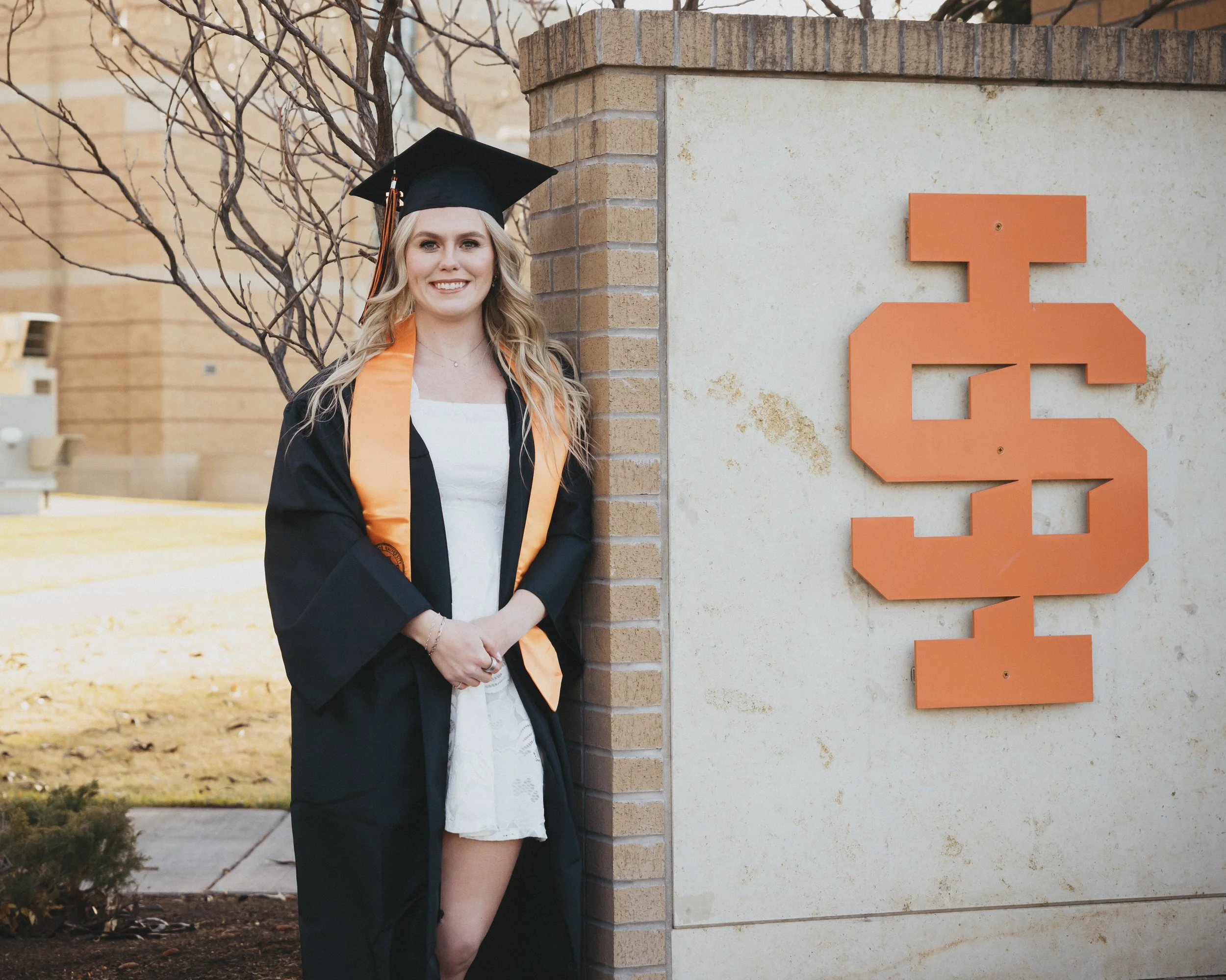 women standing at the idaho state university sign getting her graduation photos taken