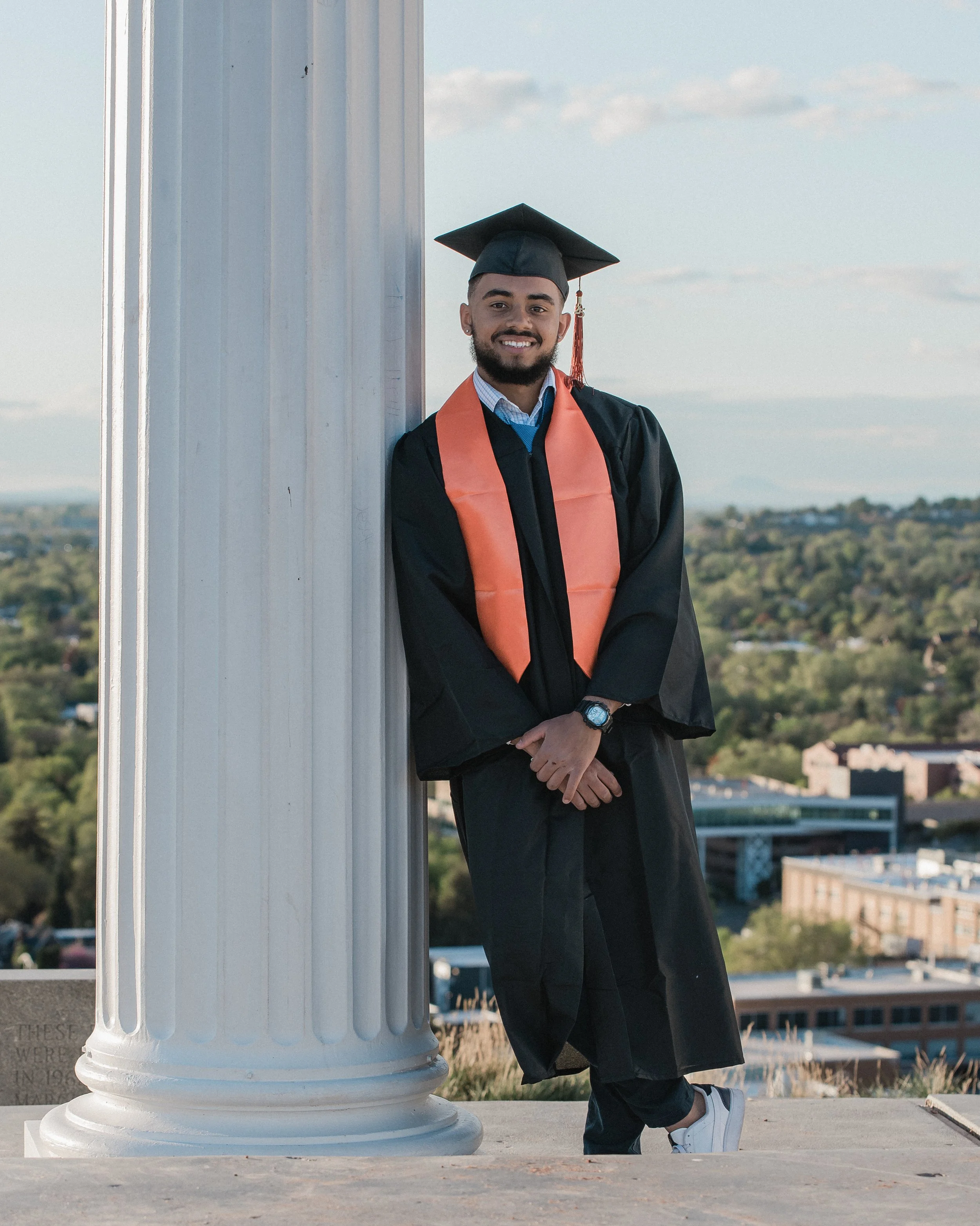 man leaning on the pillars graduating from idaho state university