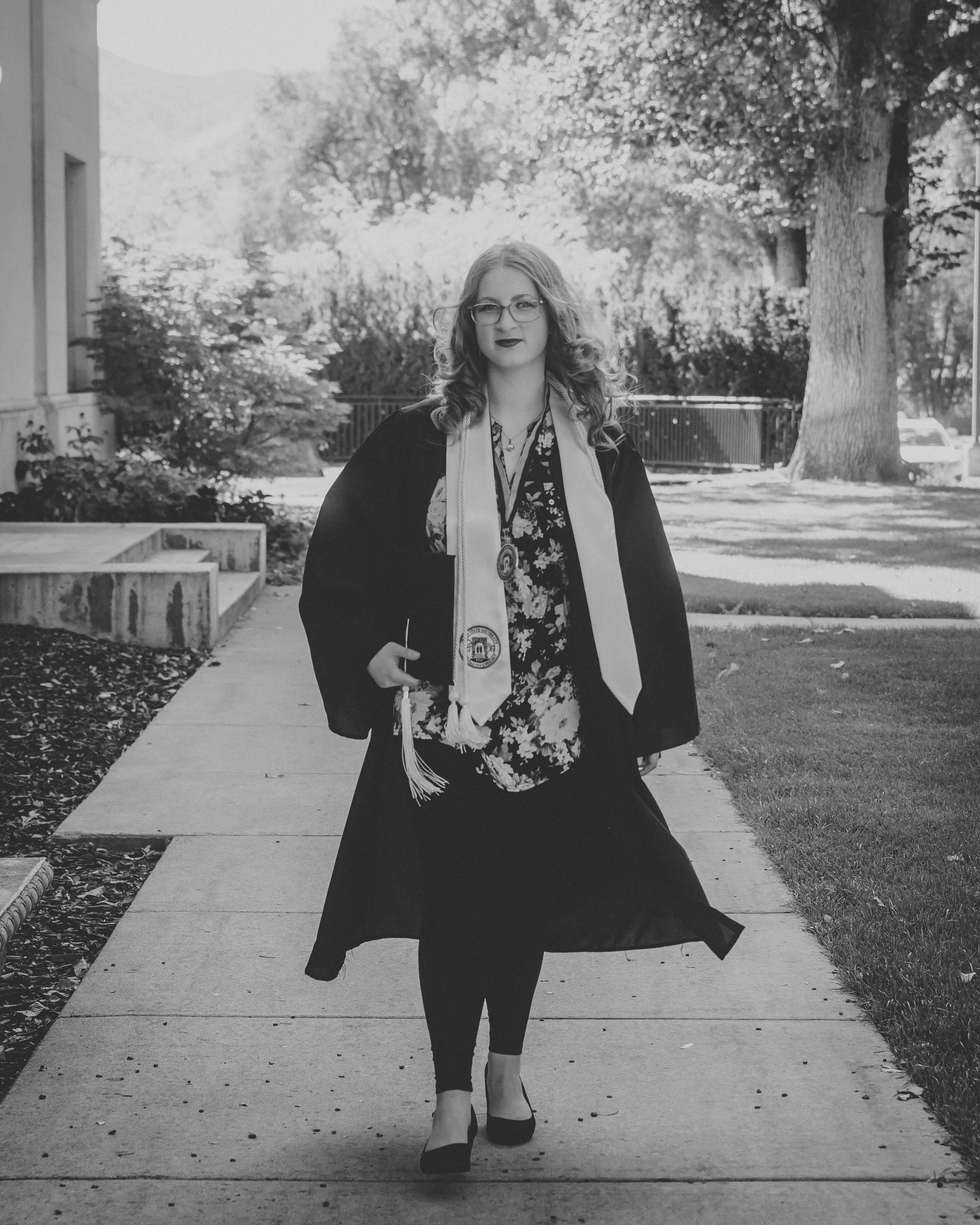 black and white image of a women walking down the side walk at Idaho state university graduation photoshoot