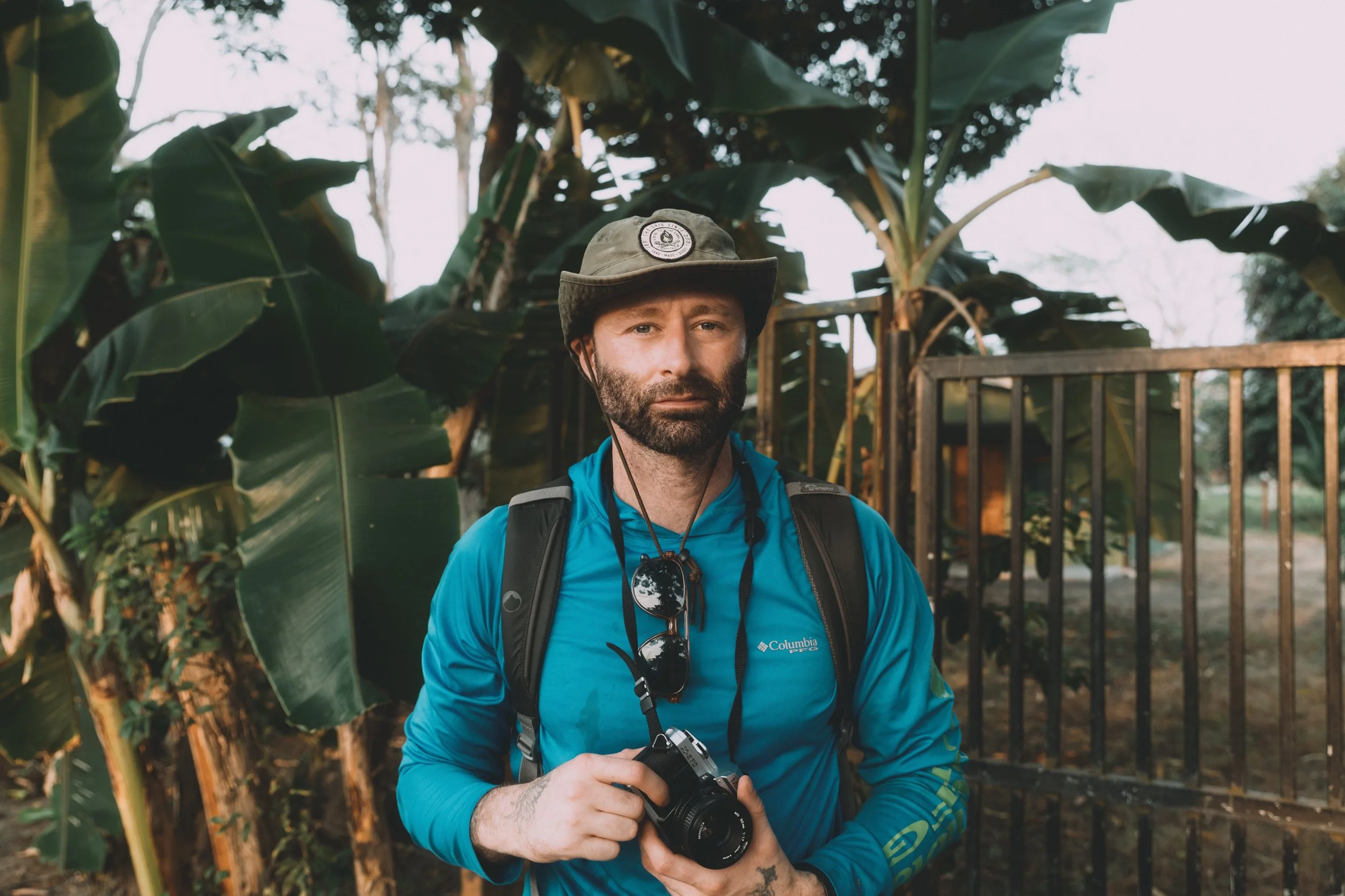man standing in the jungle with a camera documentary style photography