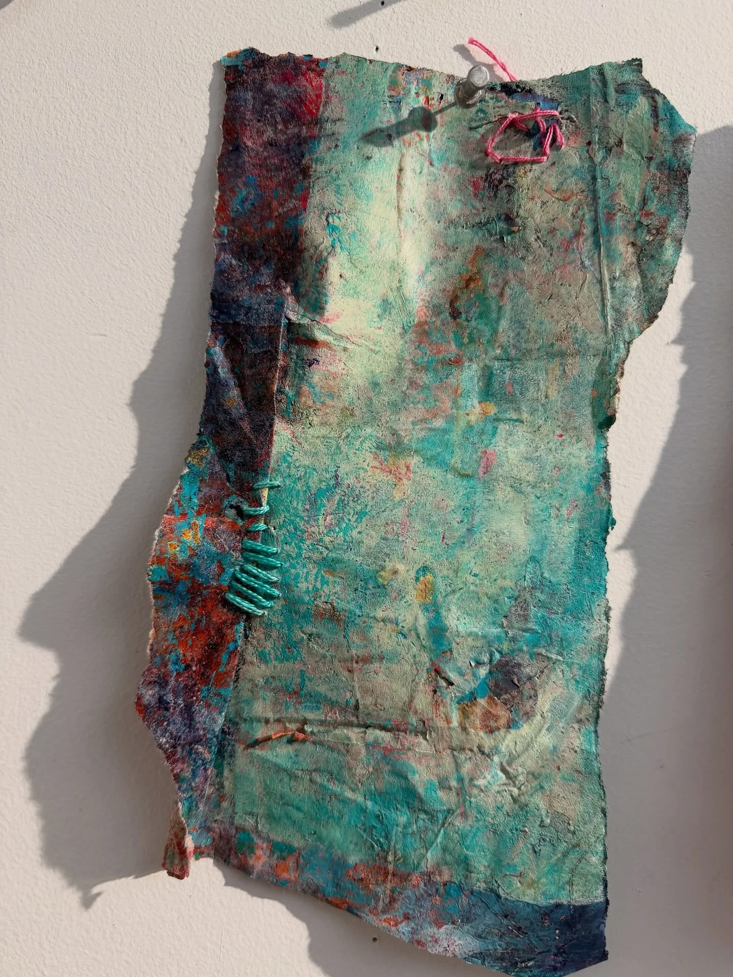 Recovered Surface
Mixed media on shaped paper
A fragment lifted from the studio table &mdash; painted, abraded, and stitched back into wholeness. The surface carries traces of what&rsquo;s been worn away and what&rsquo;s been repaired, holding color 