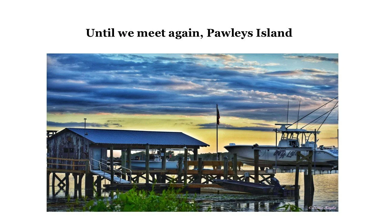 A dock with boats, a small shed, and an American flag at sunset on Pawleys Island.