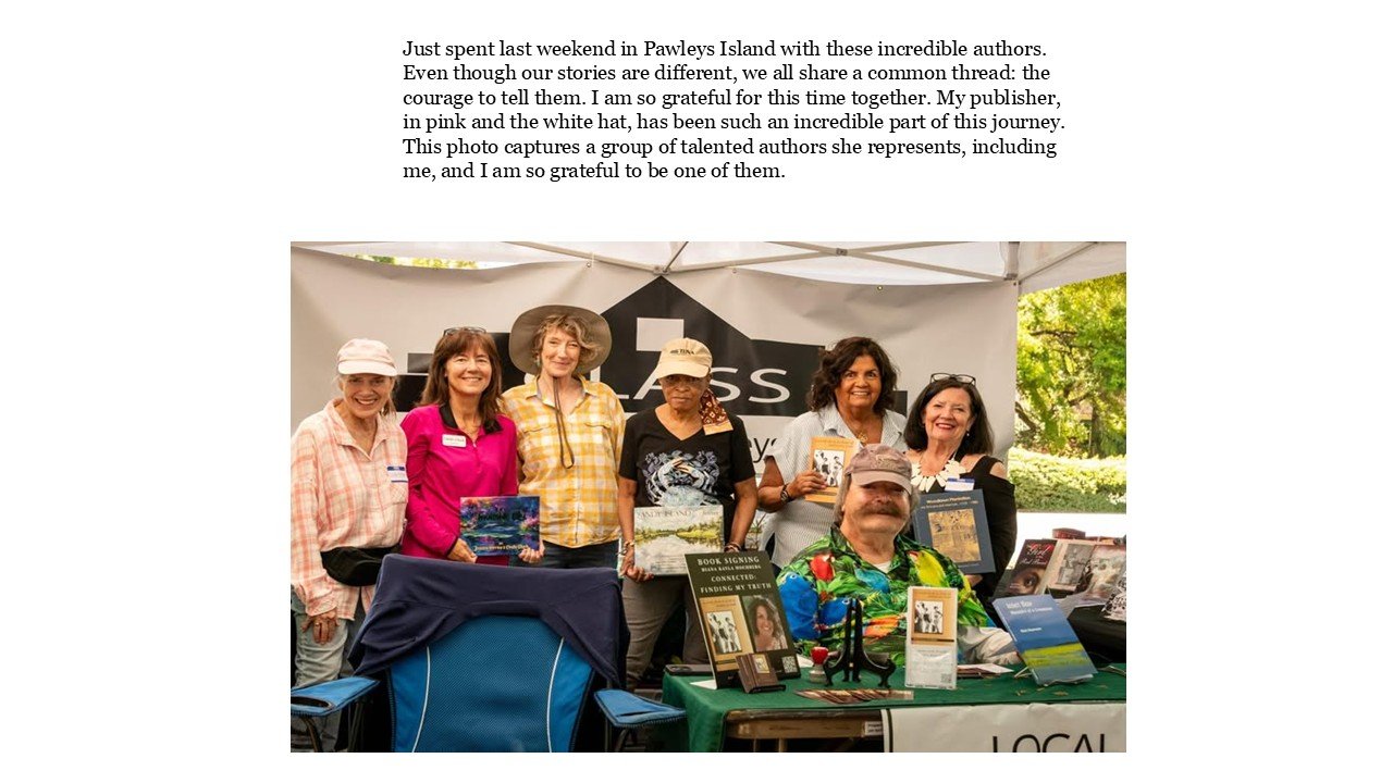 Group of six diverse authors at a book signing event, standing behind a table covered with books and promotional materials, under a canopy with a 'LOCA' banner, outdoors with greenery in the background.