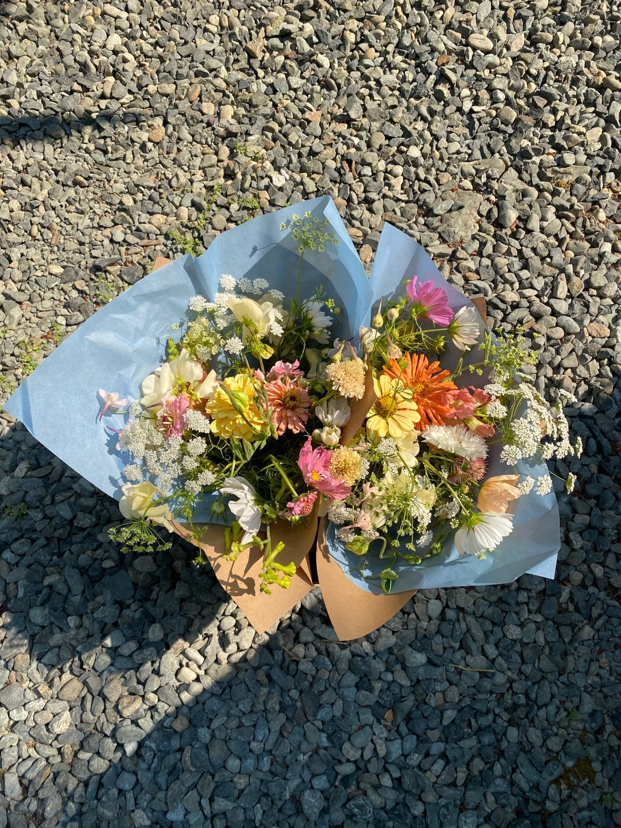 A bouquet of mixed colorful flowers on a gravel surface.
