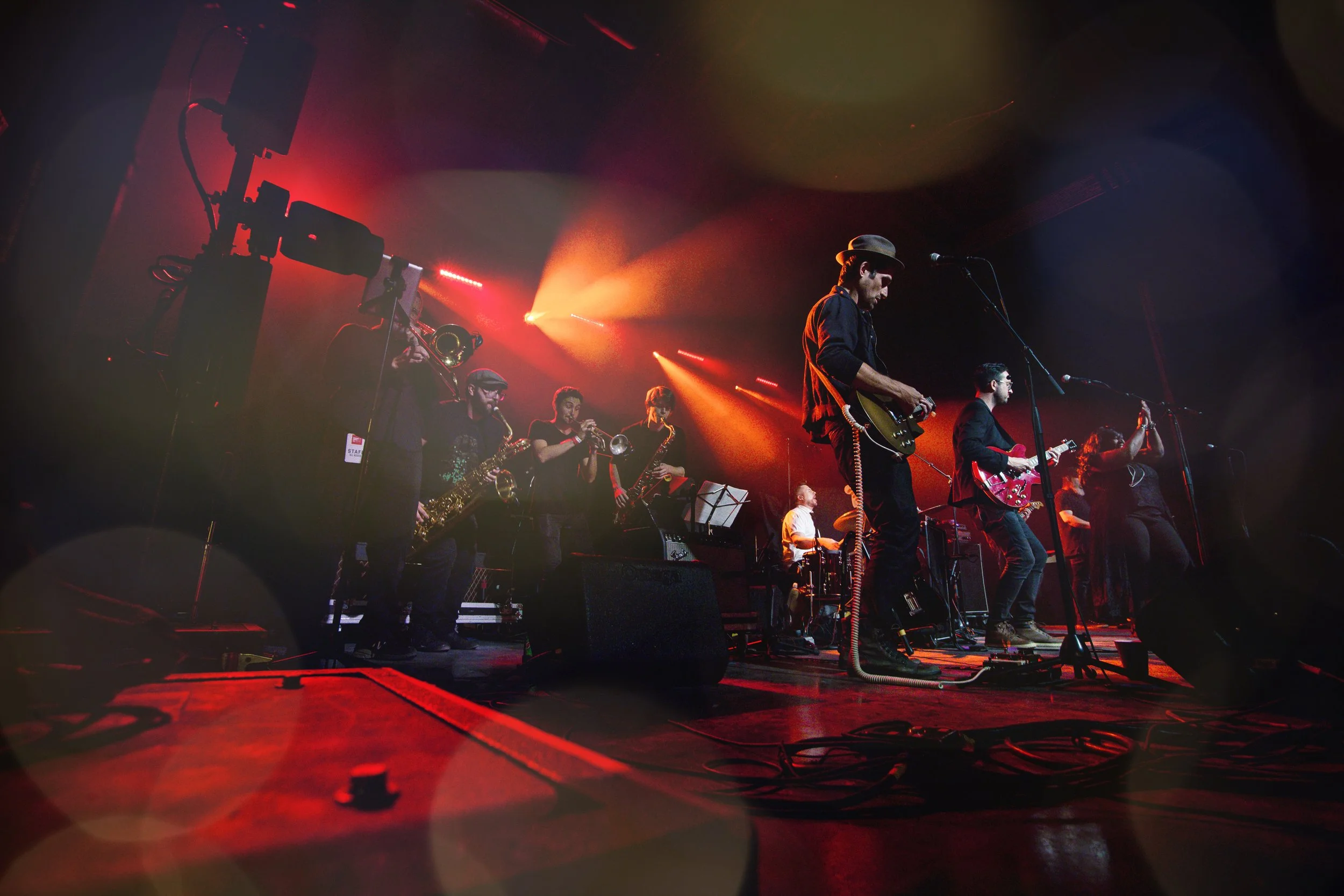 A live music concert with musicians playing instruments on stage under colorful stage lights.