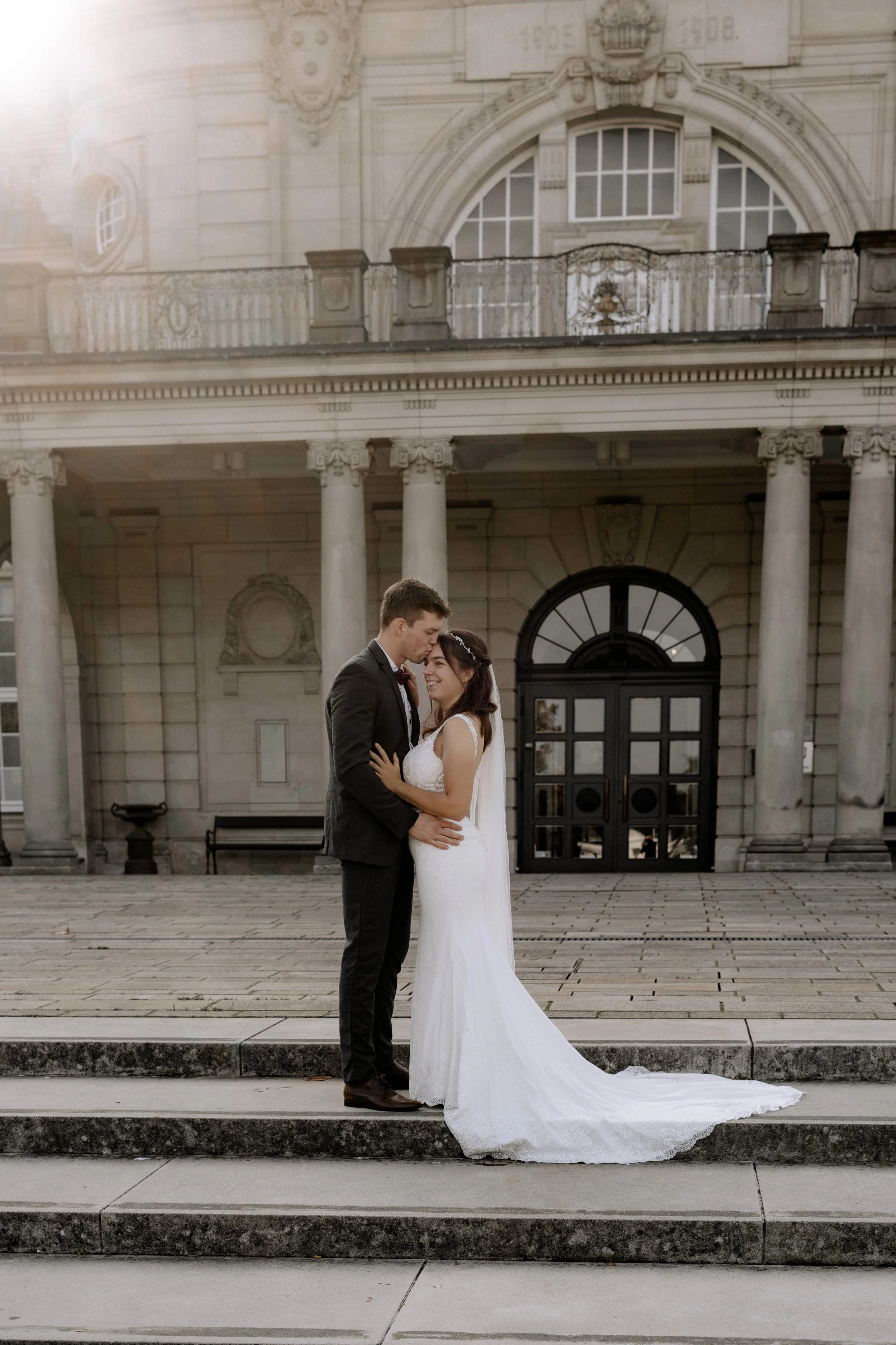 Ein frisch verheiratetes Paar steht vor einem historischen Gebäude, umarmt sich liebevoll und lächelt sich an, während sie an einem Hochzeitstag sind.