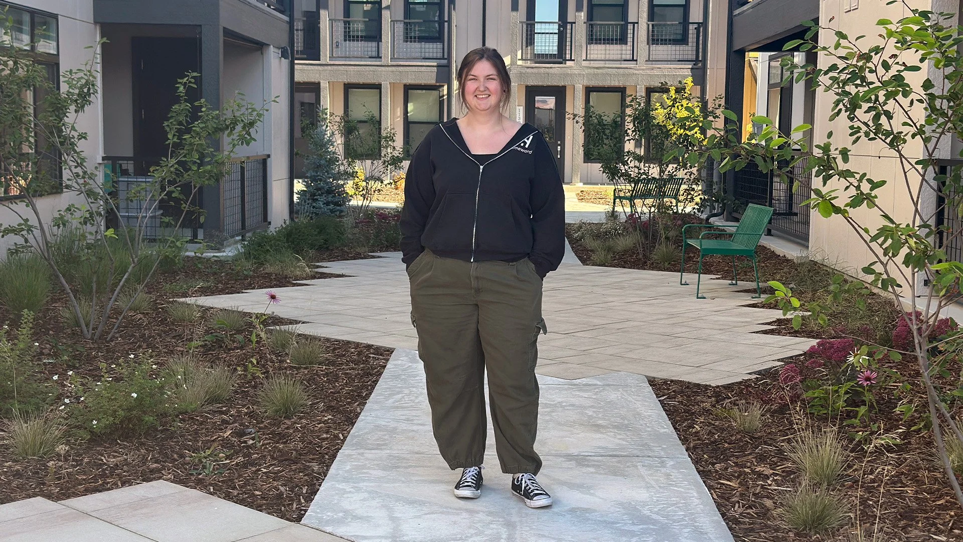 Kaitlyn standing in the courtyard outside her new Community Land Trust home