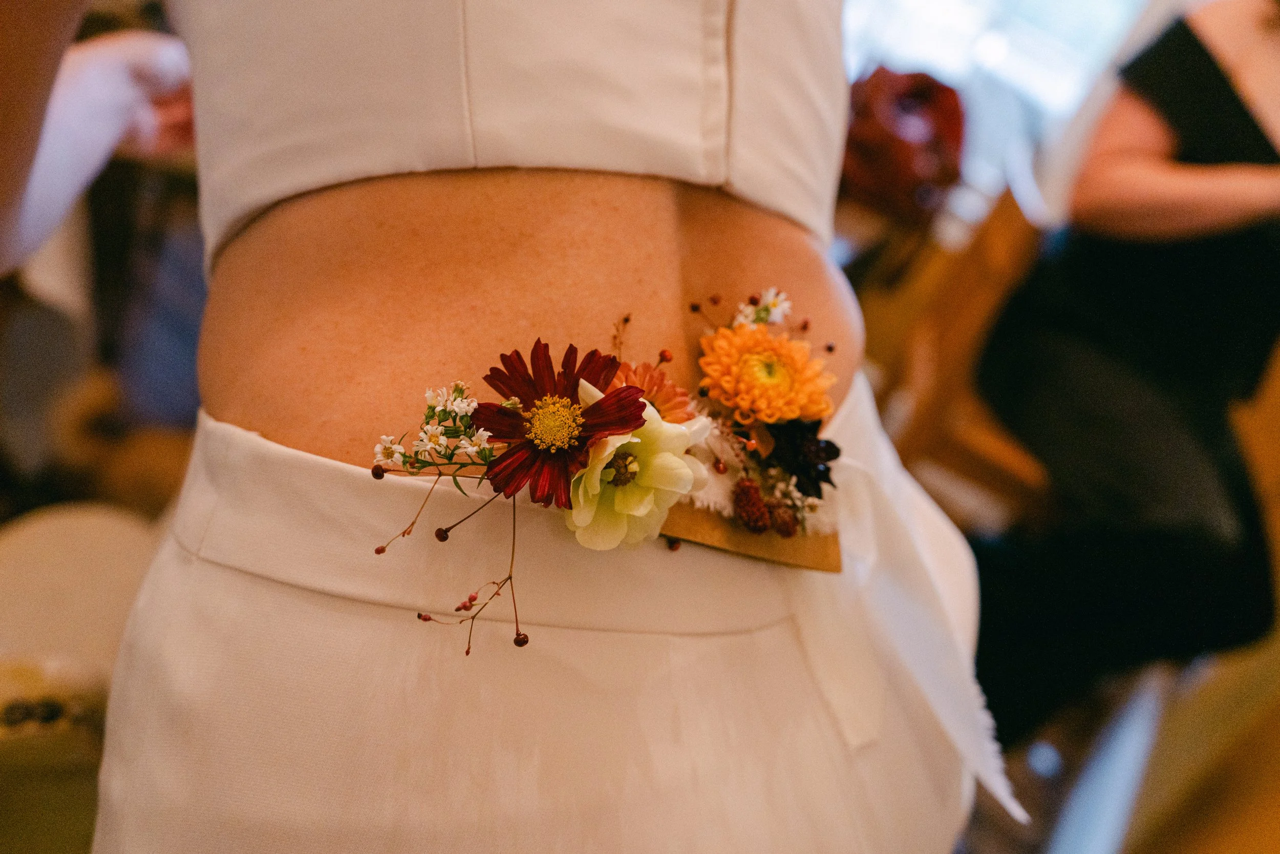 Person wearing a floral belt of pressed flowers at a wedding or celebration.