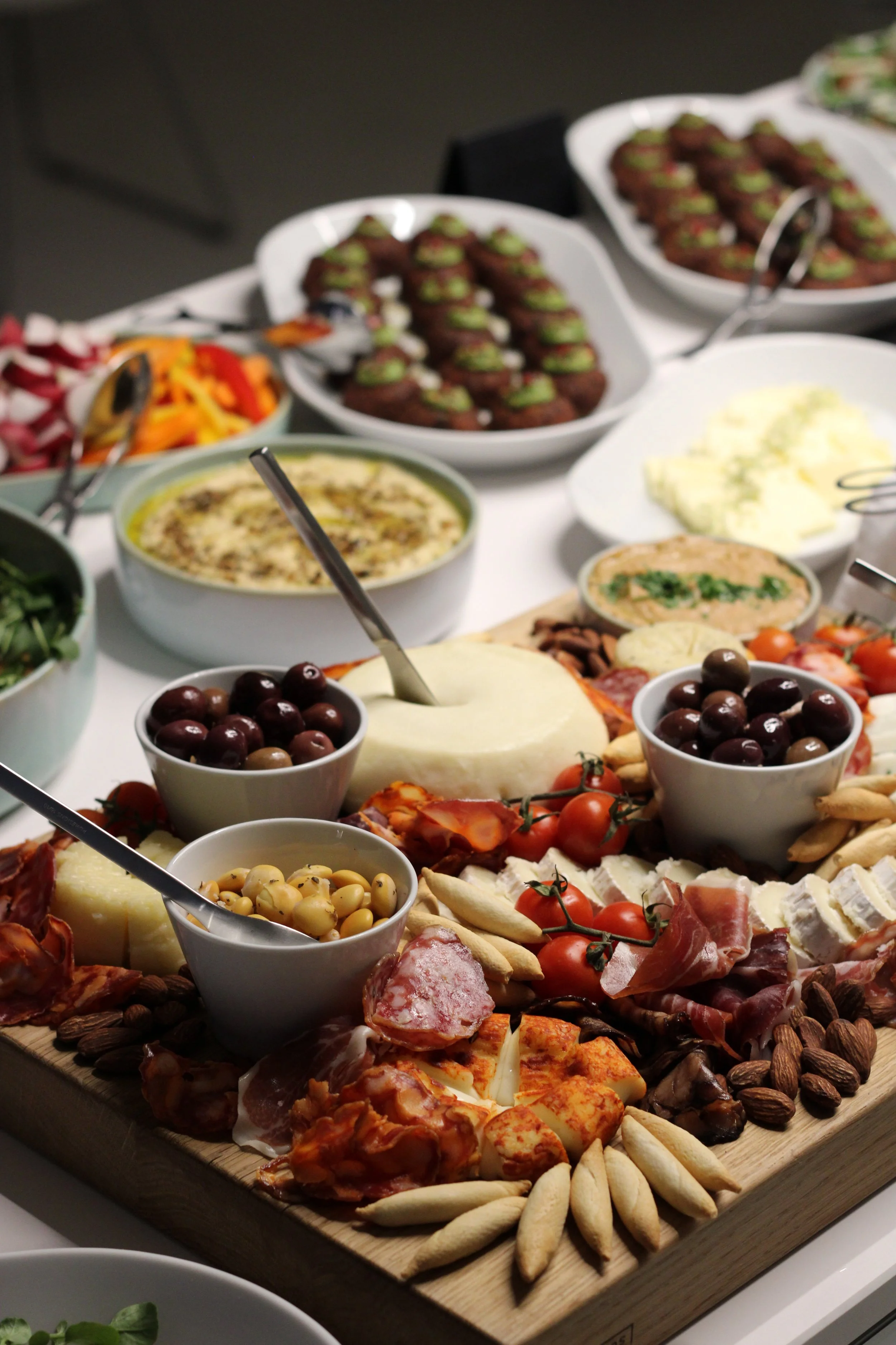 Cheese and charcuterie board with assorted breads and olives on a table.
