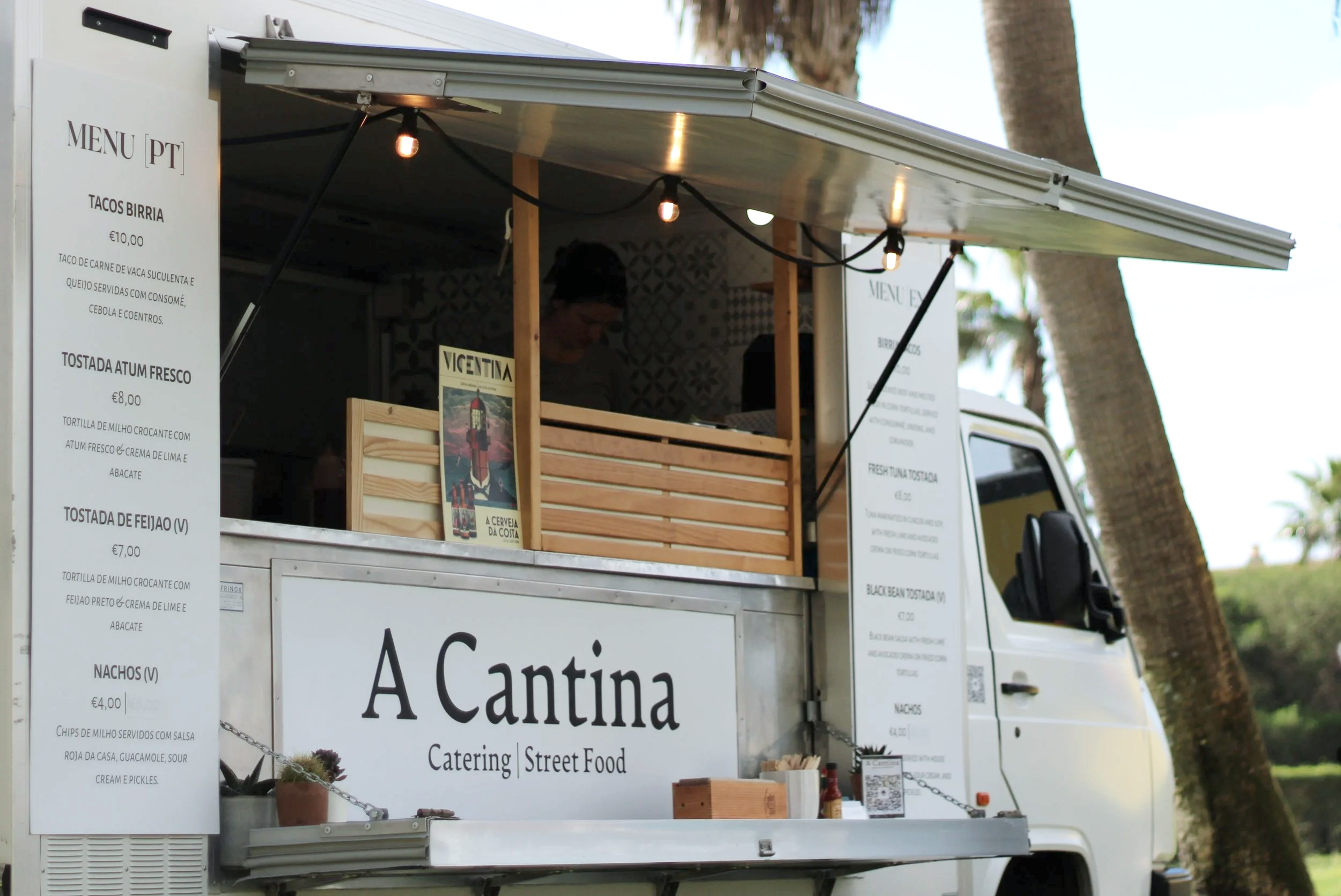 Man ordering at a food truck at night in a crowded outdoor event with people walking in the background.