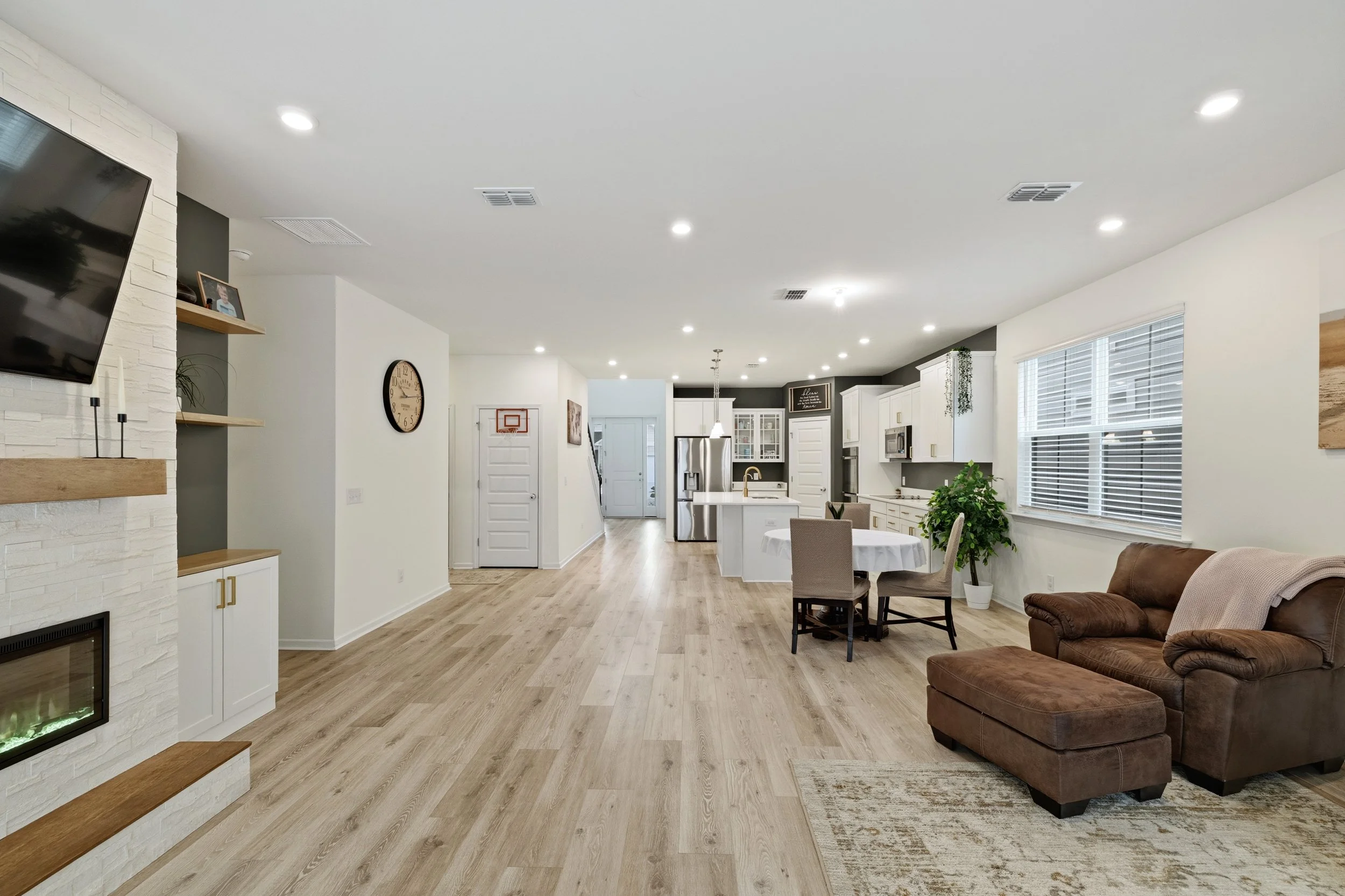 Spacious open-concept living room and kitchen in a modern home with hardwood floors, large windows, and contemporary furnishings.